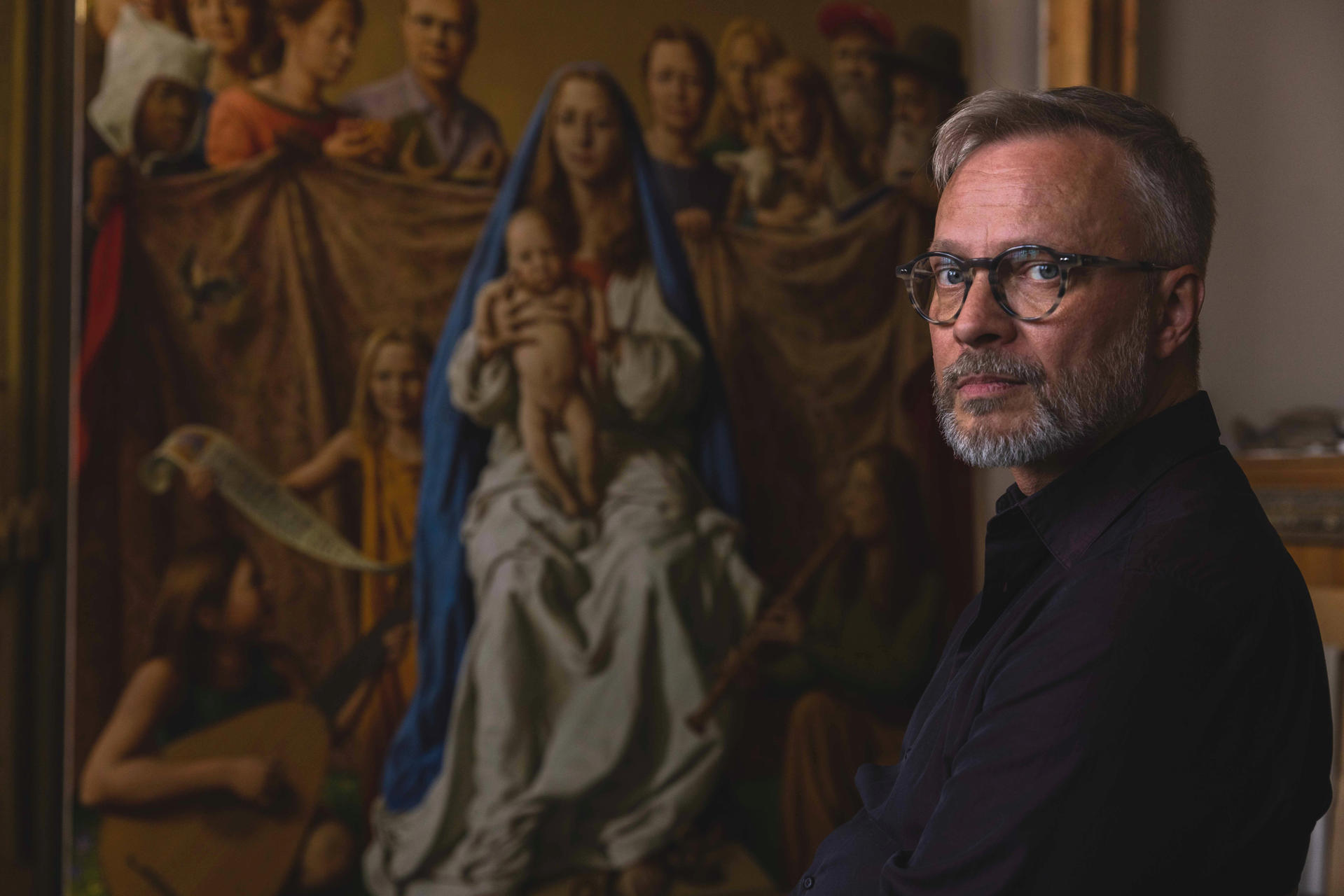 Mann mit Brille neben Renaissance-Gemälde von Madonna und Kind.