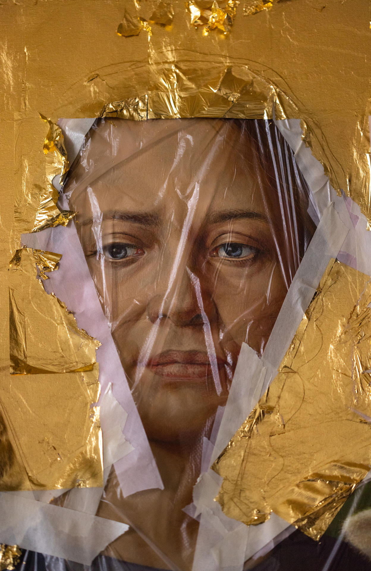 Porträt einer Frau, verdeckt von Goldfolie und Plastikfolie.