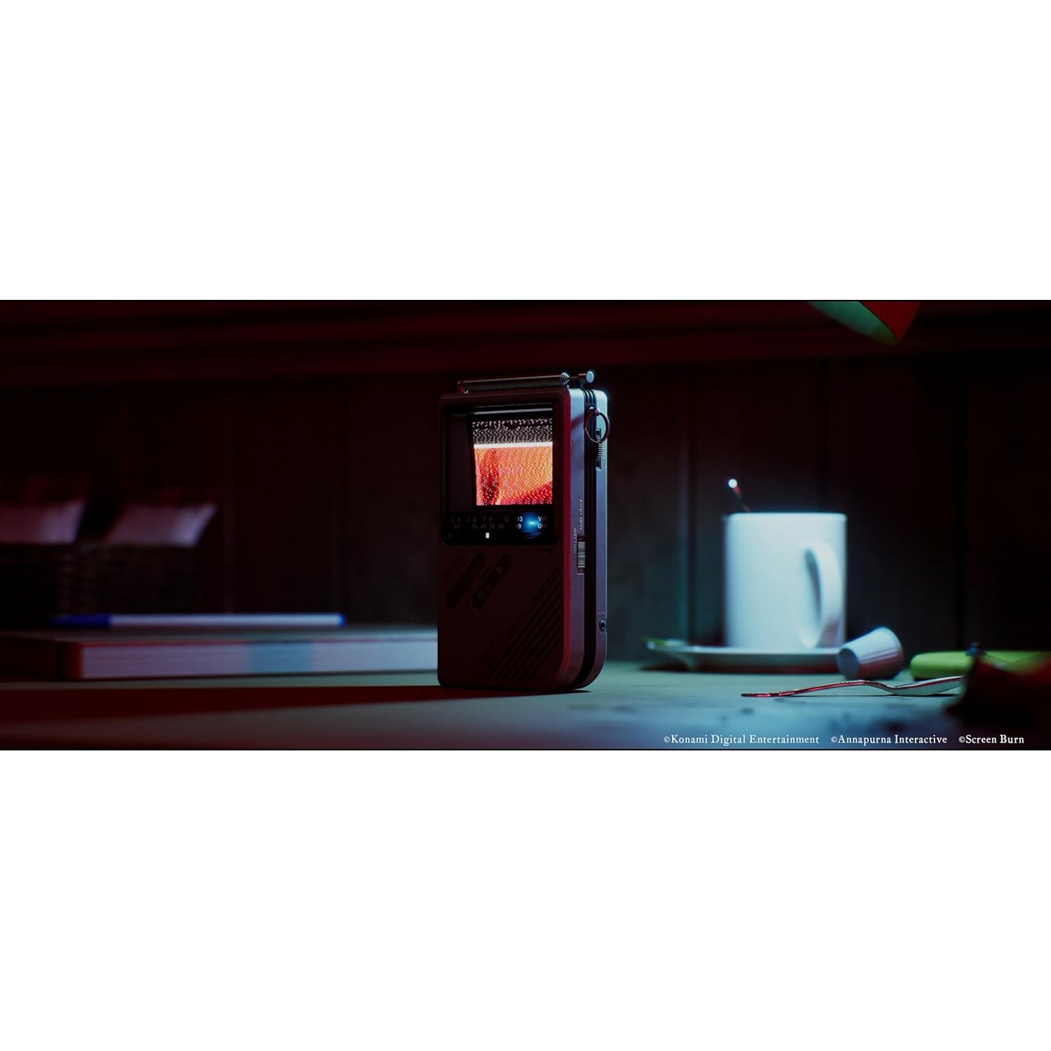 A red handheld device with a screen sits on a table next to a mug.
