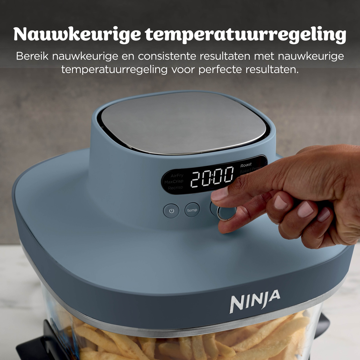 Une main ajuste une friteuse à air Ninja bleue contenant des frites.