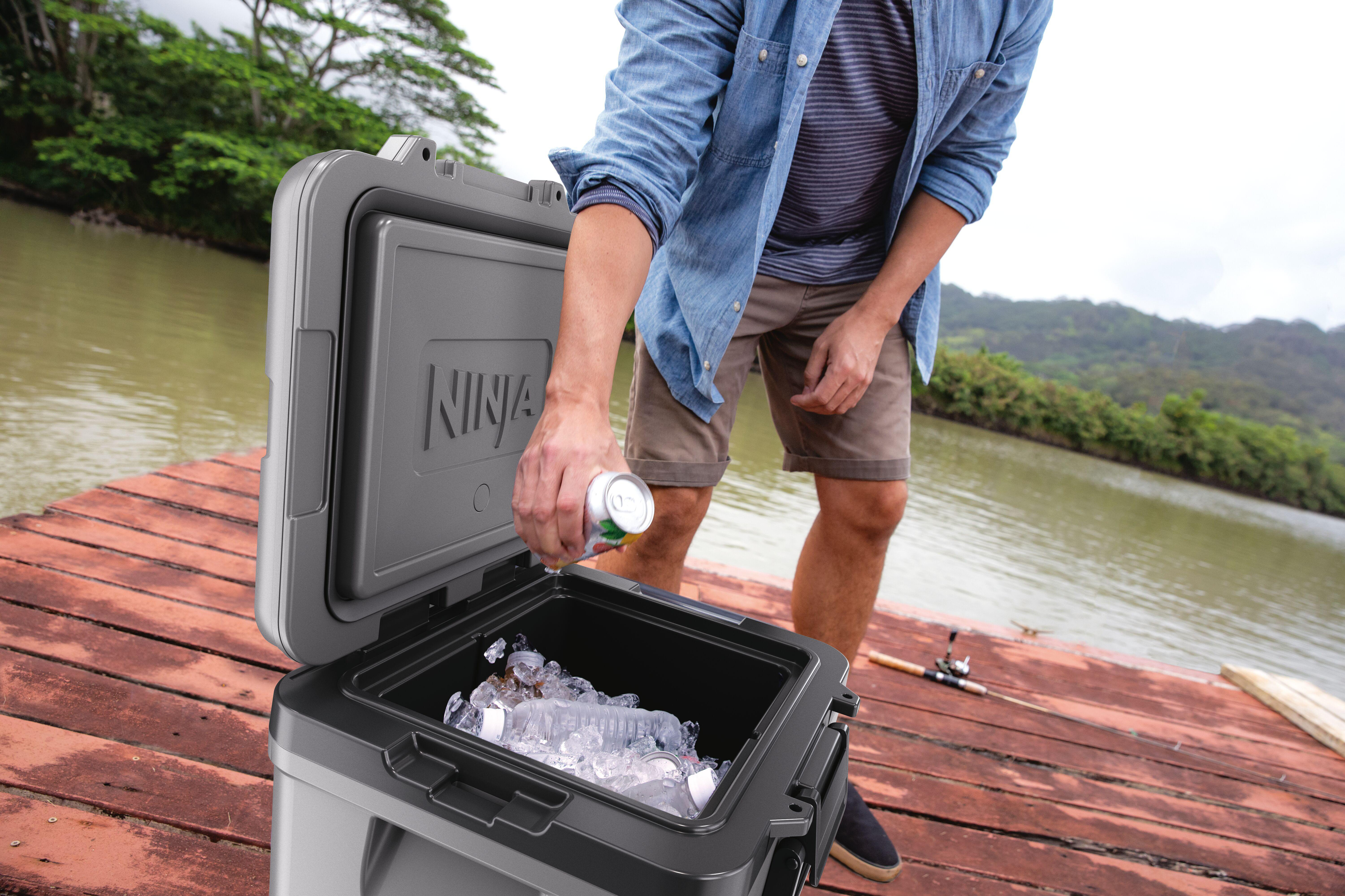 Mann legt Dose in eine gefüllte Kühlbox am Wasser.