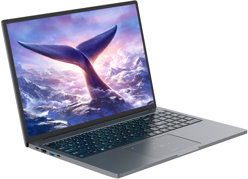 Laptopon bálnafarok tör elő hófedte hegyekből, színes ég alatt.