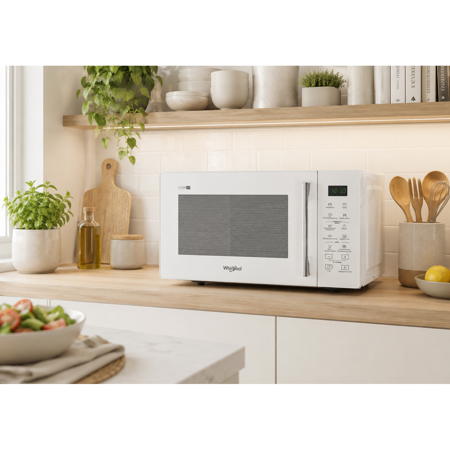 Un forno a microonde bianco Whirlpool su un piano di lavoro in legno con insalata e limone.