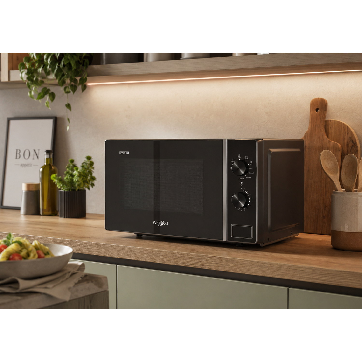 Un microonde Whirlpool nero si trova su un bancone di legno con utensili da cucina.