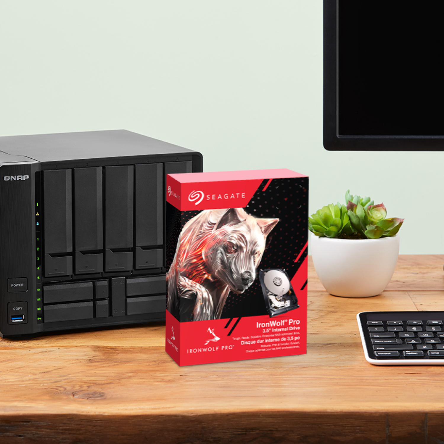 Ein QNAP-NAS und eine Seagate IronWolf Pro Festplatte stehen auf einem Holztisch.