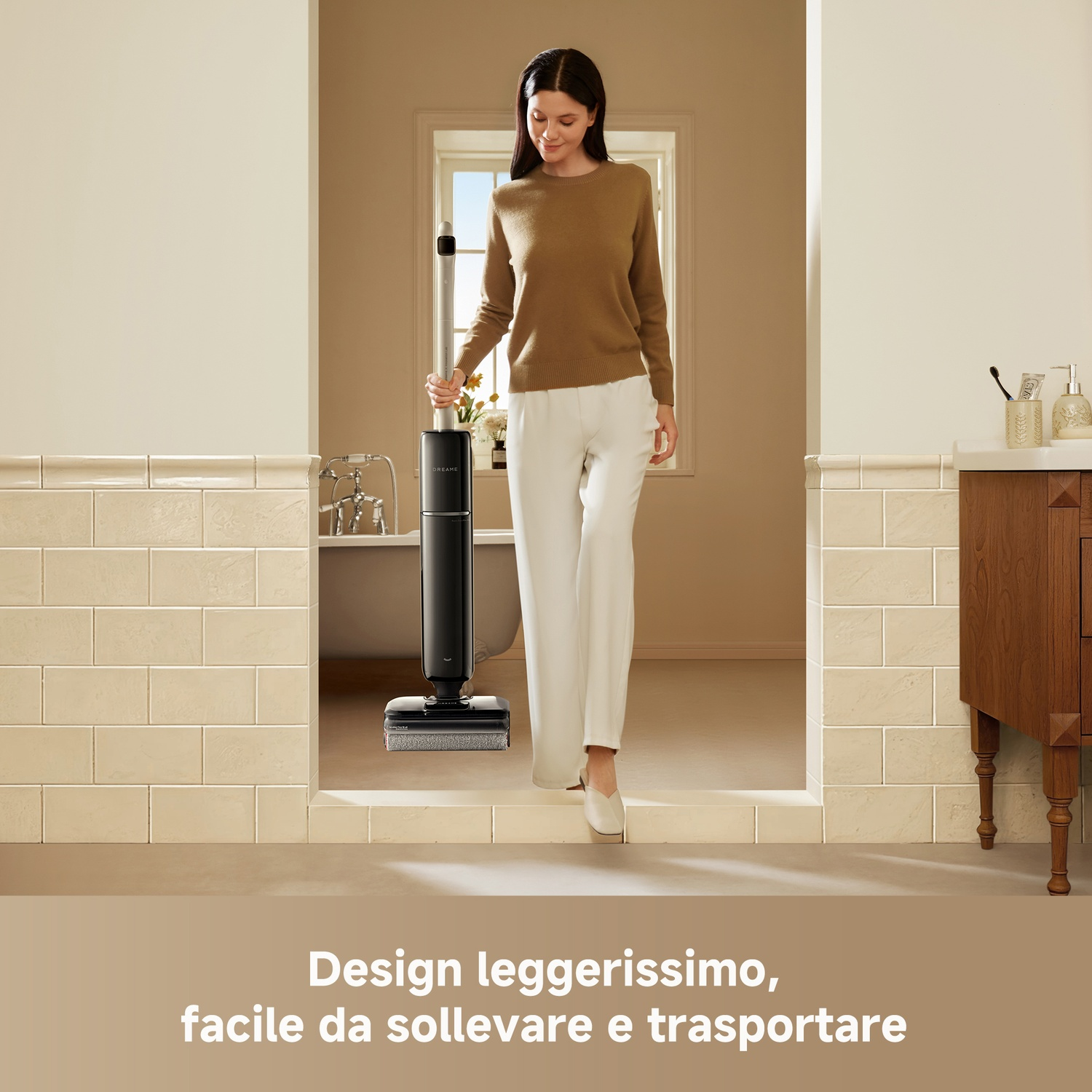 Donna in maglione marrone e pantaloni bianchi con aspirapolvere nero in bagno.