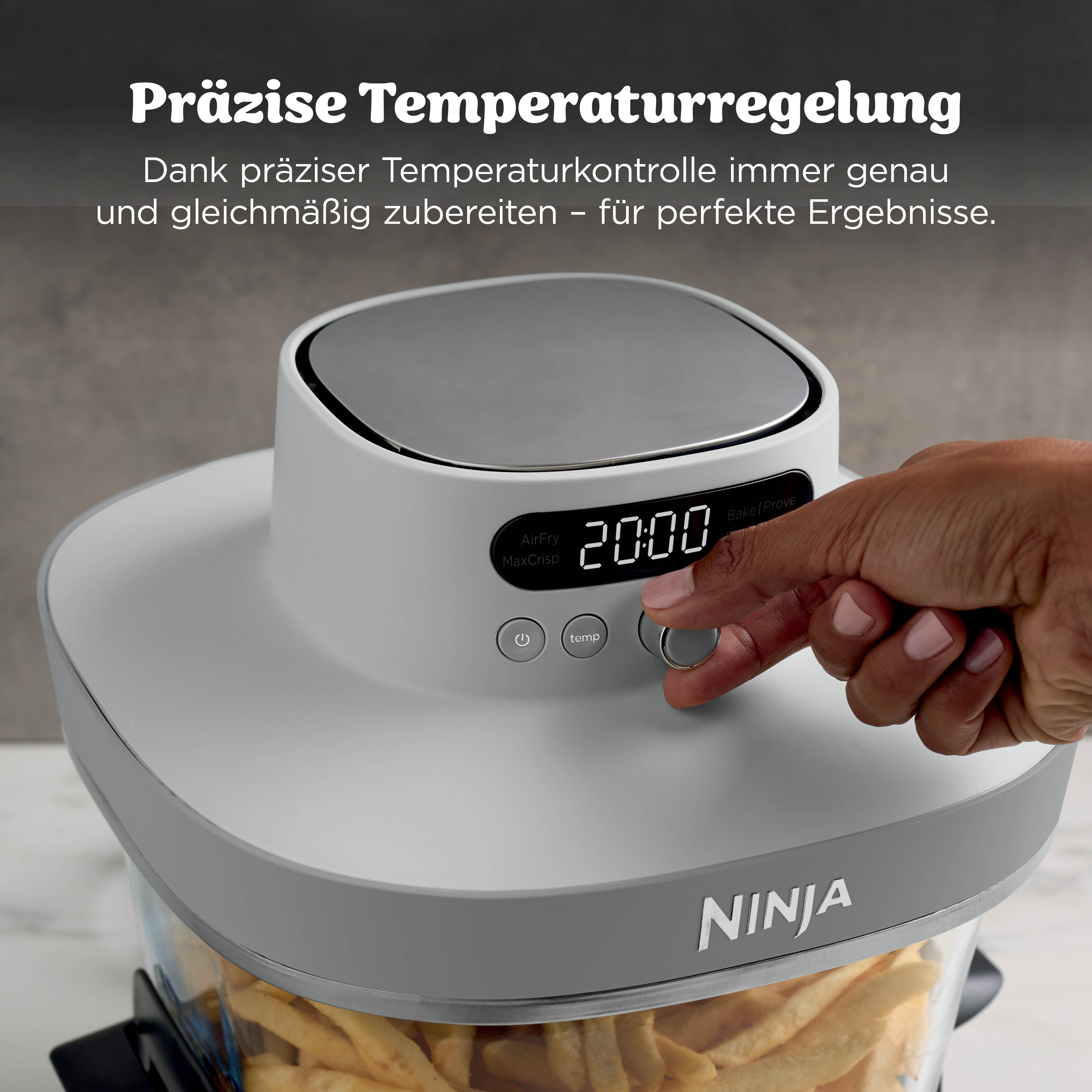 Une main ajuste une friteuse à air Ninja remplie de frites.