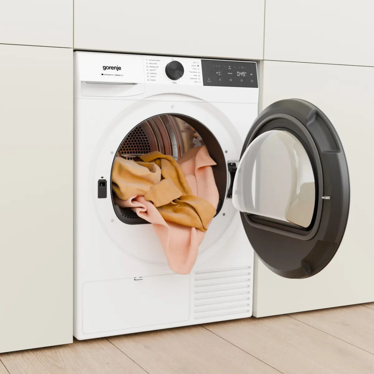 Egy fehér Gorenje szárítógép nyitott ajtóval, benne narancssárga ruhákkal.