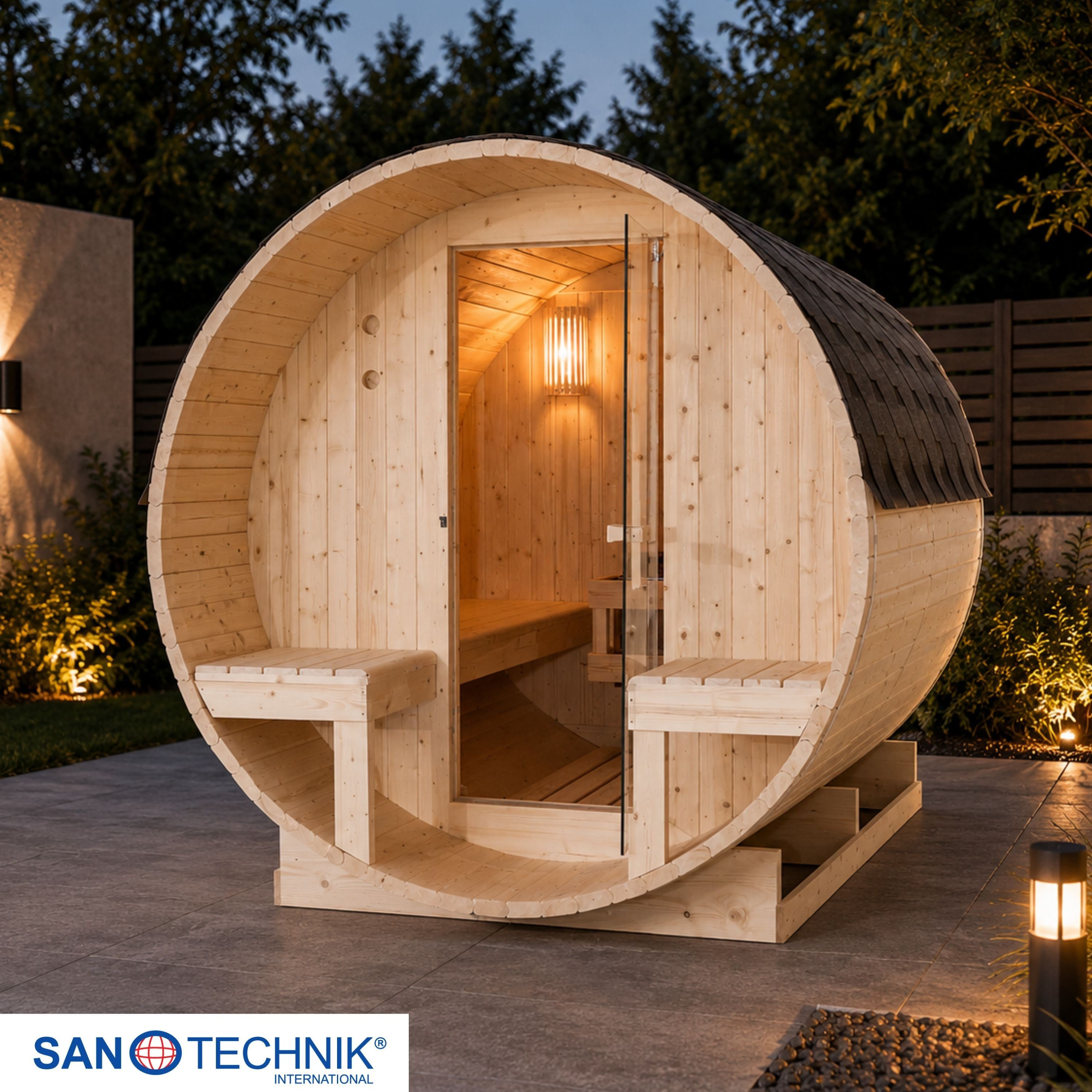 Holzfass-Sauna im Freien bei Nacht, beleuchtet von Außenlampen.