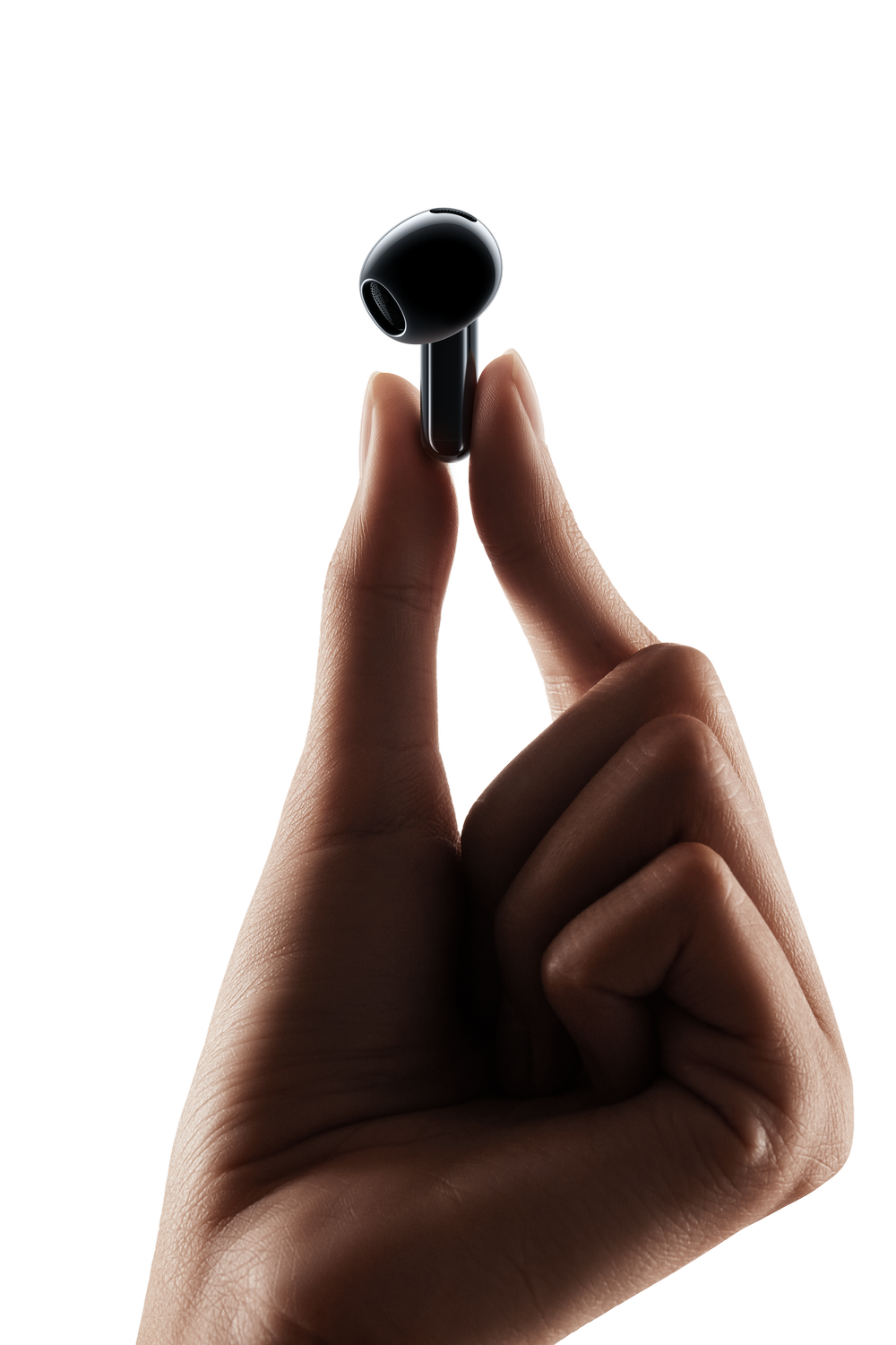 Una mano sostiene un solo auricular negro sobre fondo negro.