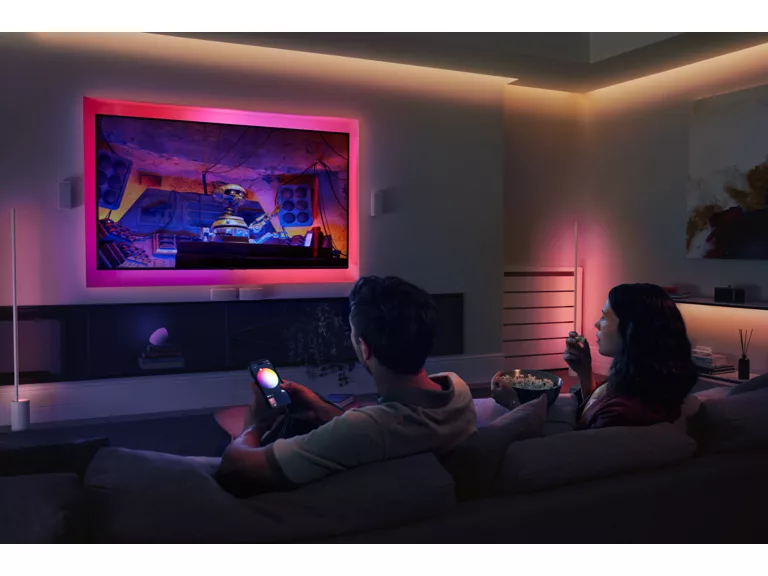 Una pareja se sienta en un sofá viendo la televisión, con la luz del televisor brillando en rojo.