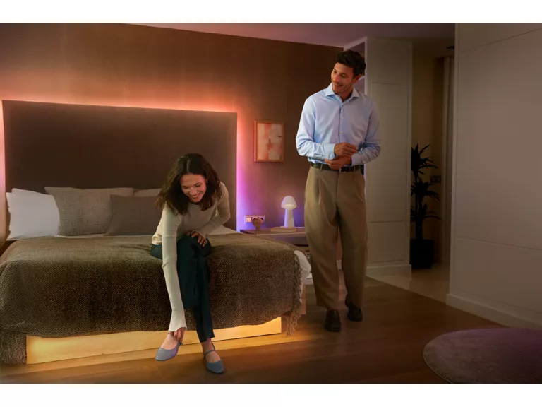 Un hombre y una niña en un dormitorio con iluminación ambiental.