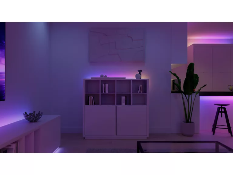 Una sala de estar con luz púrpura, estantería, planta y taburete.