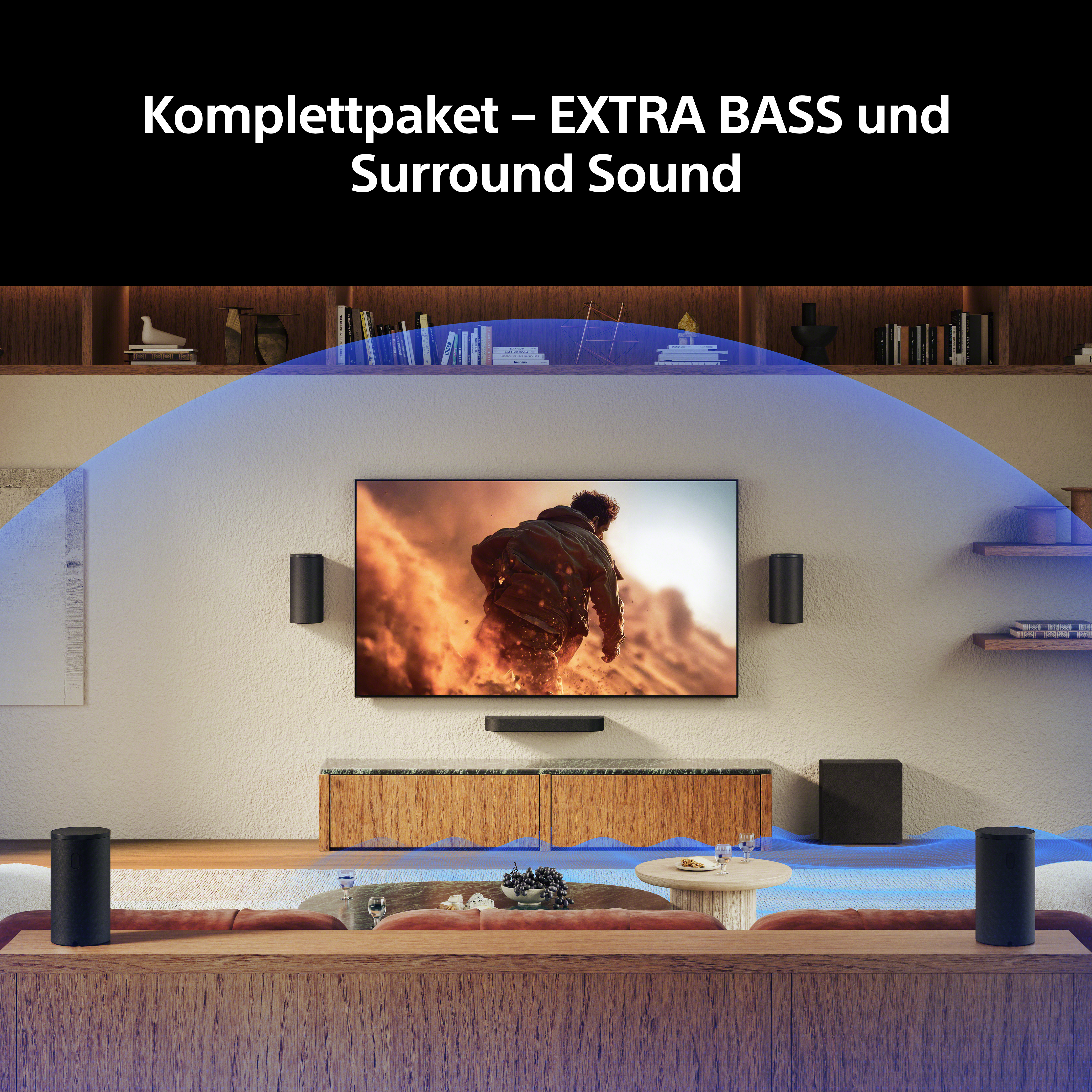 Ein Wohnzimmer mit Fernseher, Lautsprechern und Text "Komplettpaket - EXTRA BASS und Surround Sound".