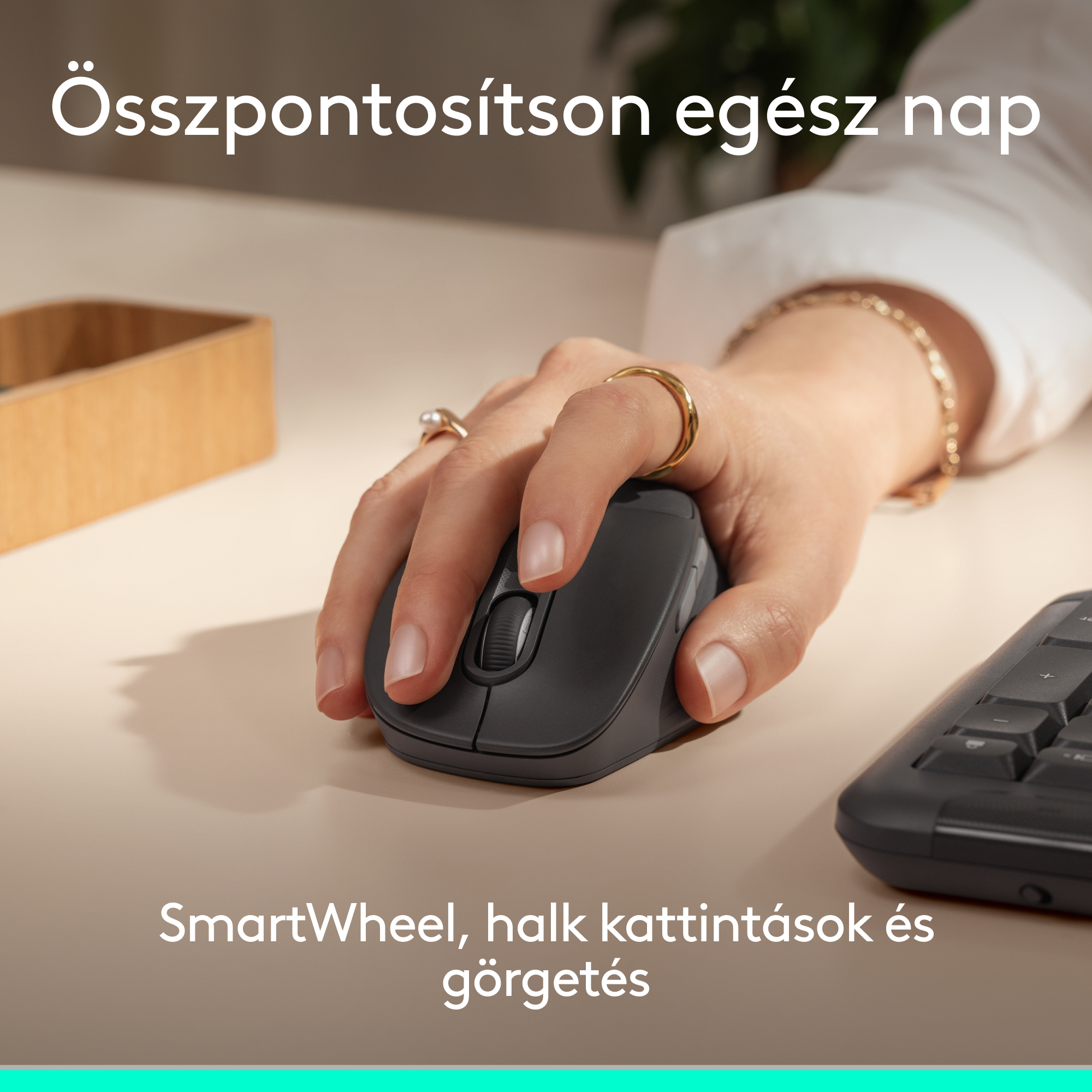 Egy kéz sötét egeret használ világos asztalon, billentyűzet mellett.