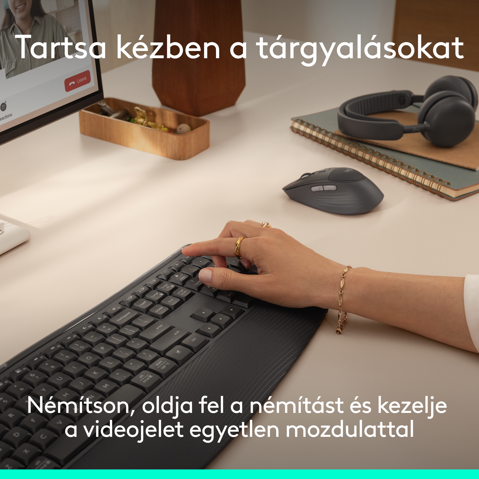 Egy kéz billentyűzeten gépel, fejhallgató, egér és jegyzetfüzet mellett.
