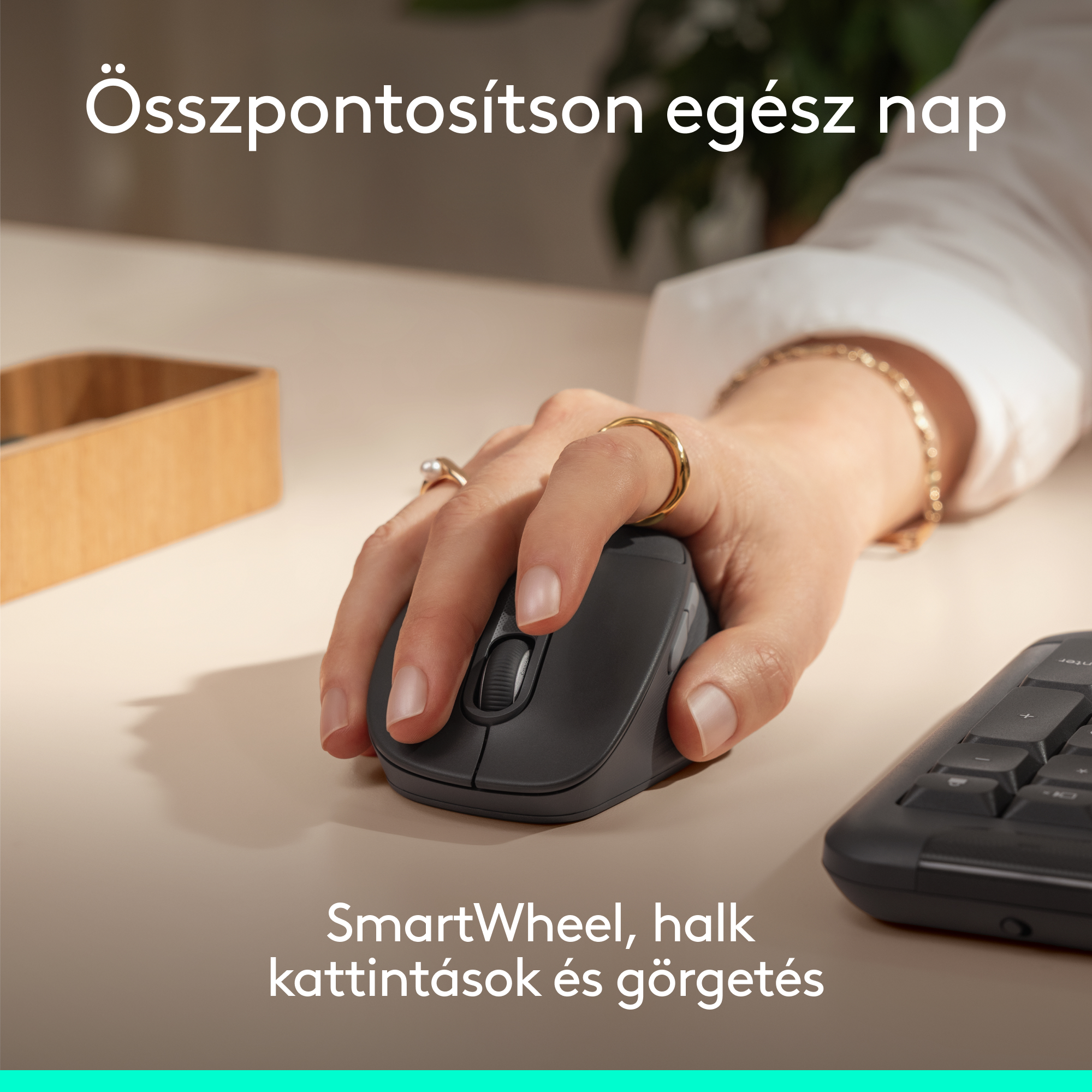 Egy kéz szürke egeret használ, mellette billentyűzet és fa tároló.