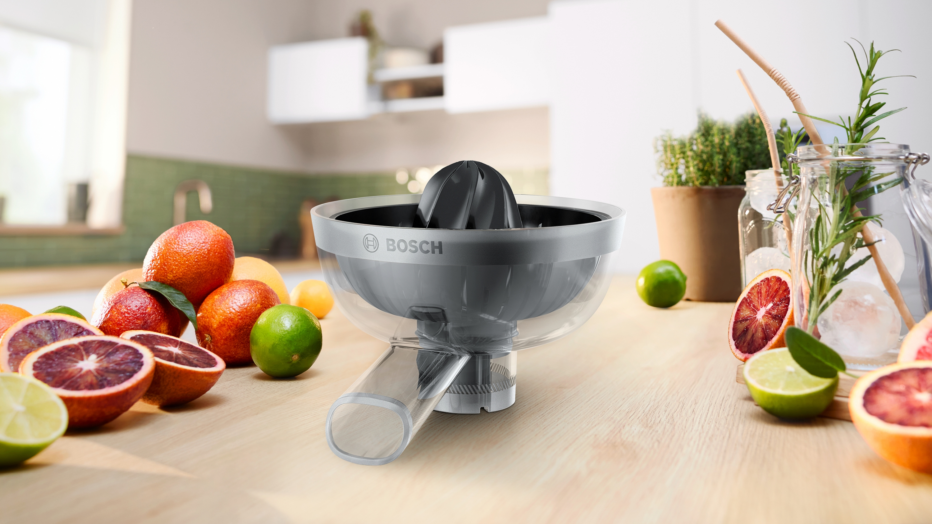 Ein Bosch Zitruspresse steht auf einem Holztisch mit Orangen, Limetten und Kräutern.