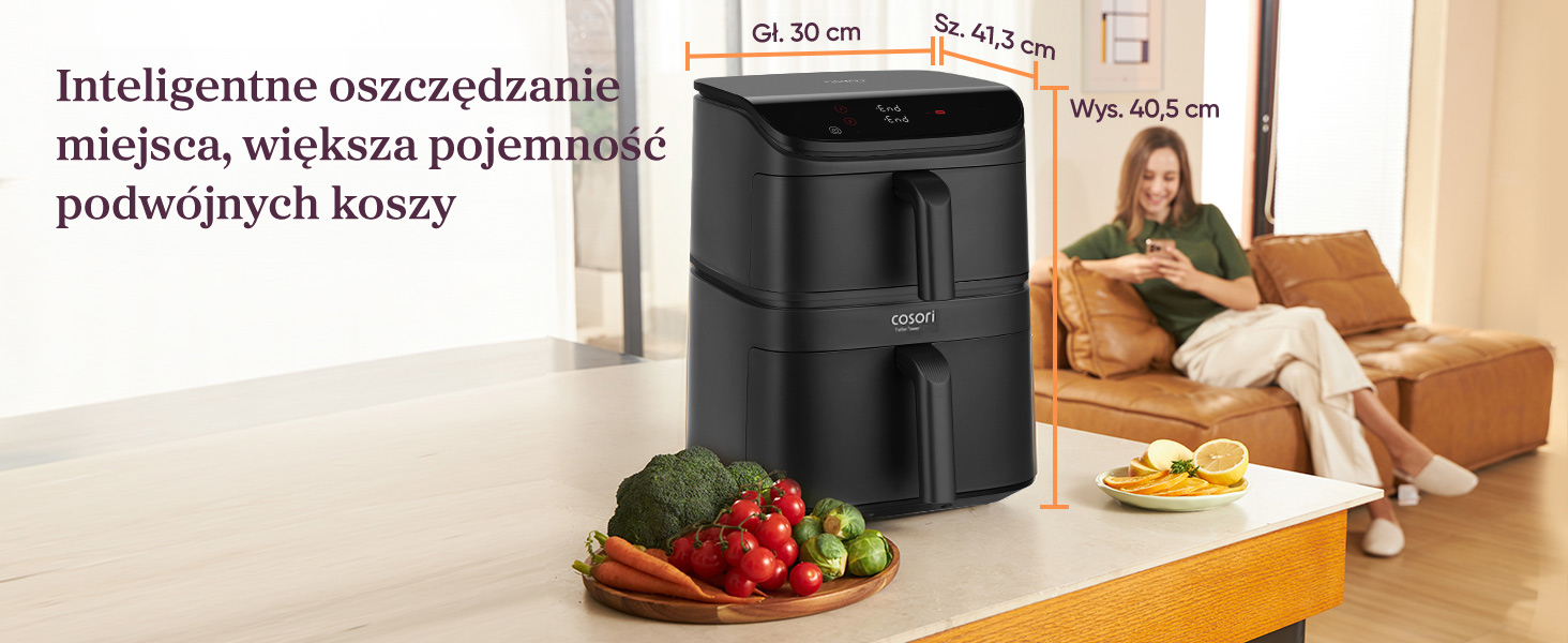 Czarna frytkownica beztłuszczowa z podwójnym koszem, z warzywami i owocami na blacie.