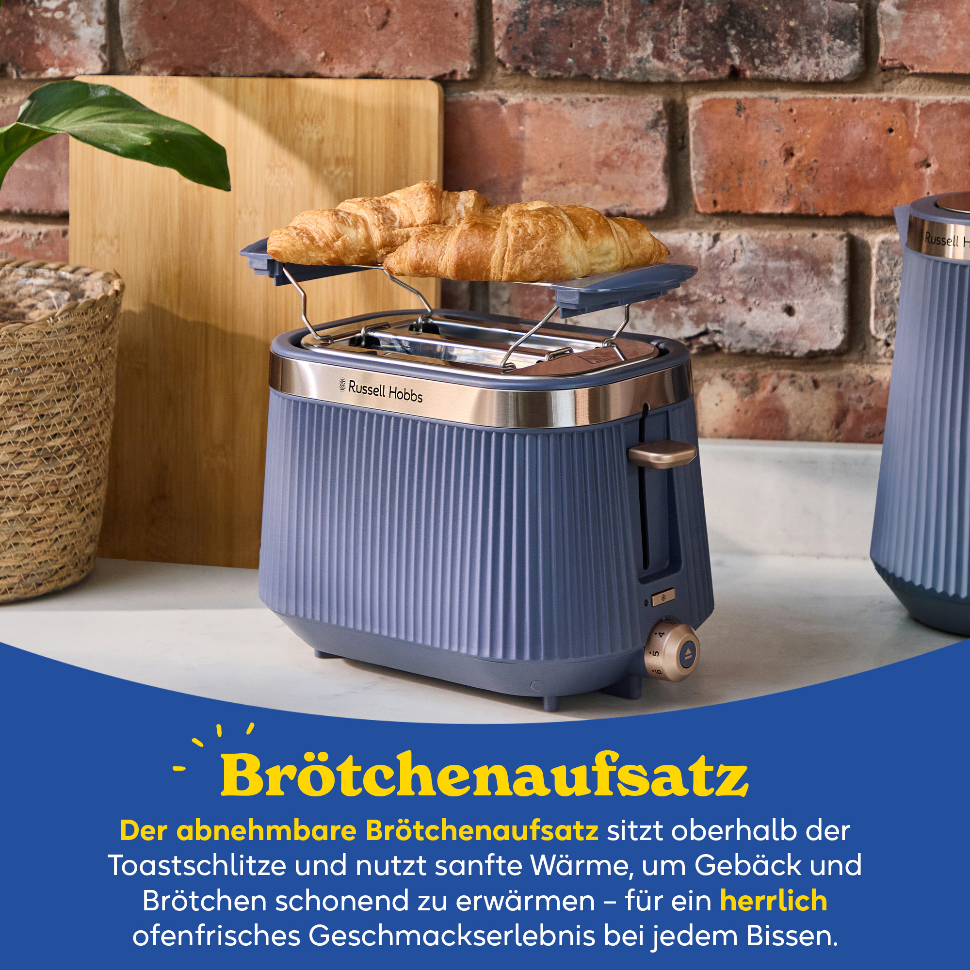 Ein blauer Toaster mit Brötchenaufsatz und zwei Croissants.