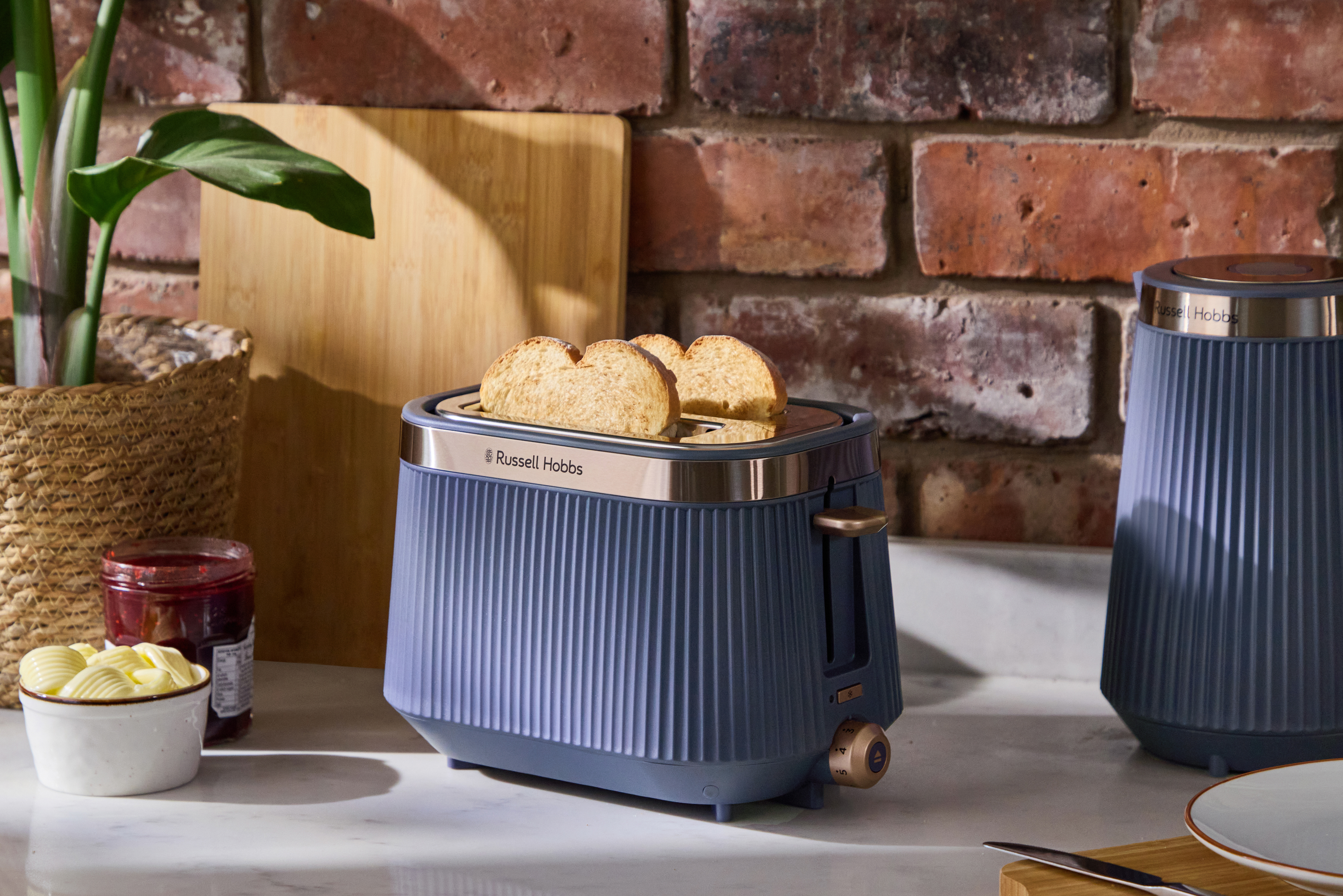 Ein blauer Russell Hobbs Toaster mit Toastbrot, Marmelade und Butter.