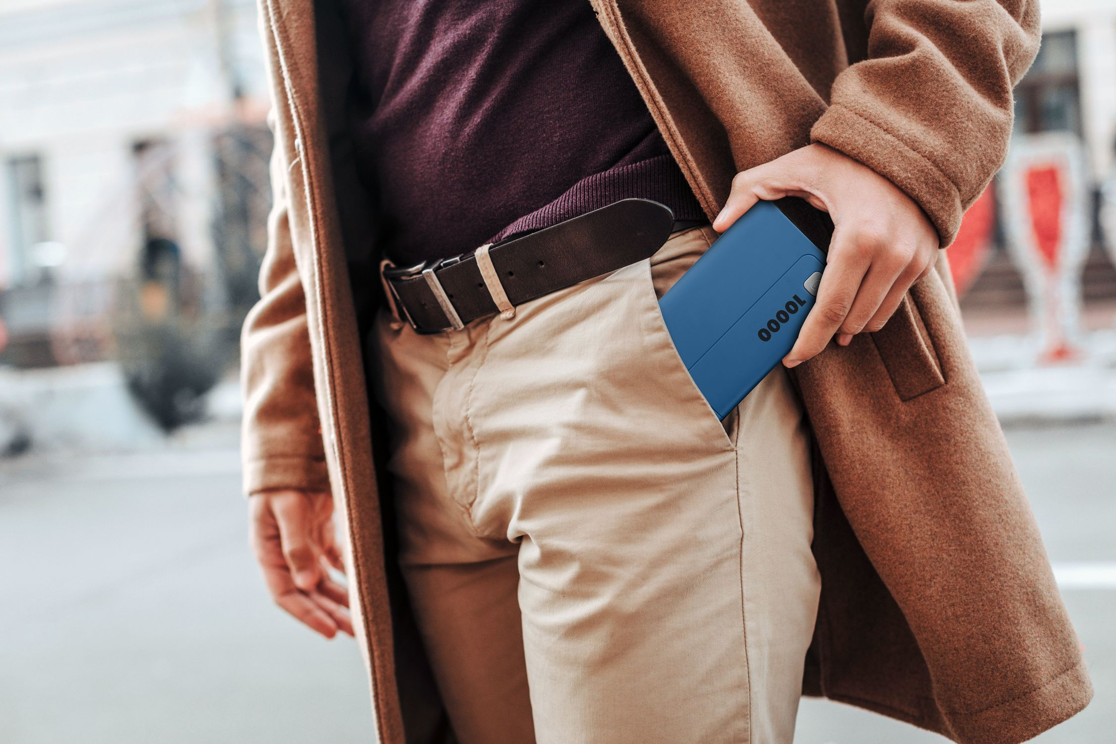 Un hombre se mete un cargador portátil azul con "10000" en el bolsillo.