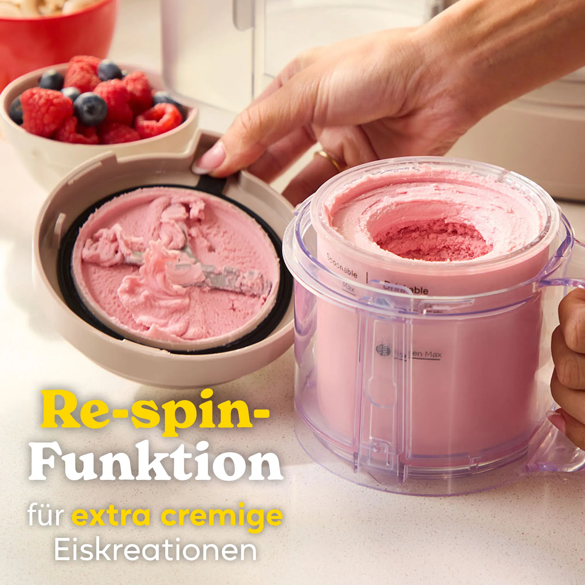 Ein Eisbereiter mit rosa Eis und Beeren daneben.