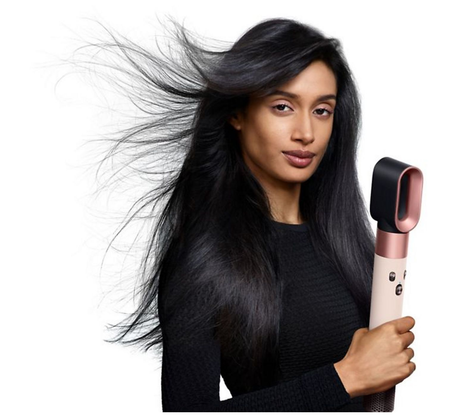 Femme aux longs cheveux noirs tient un sèche-cheveux rose et noir.