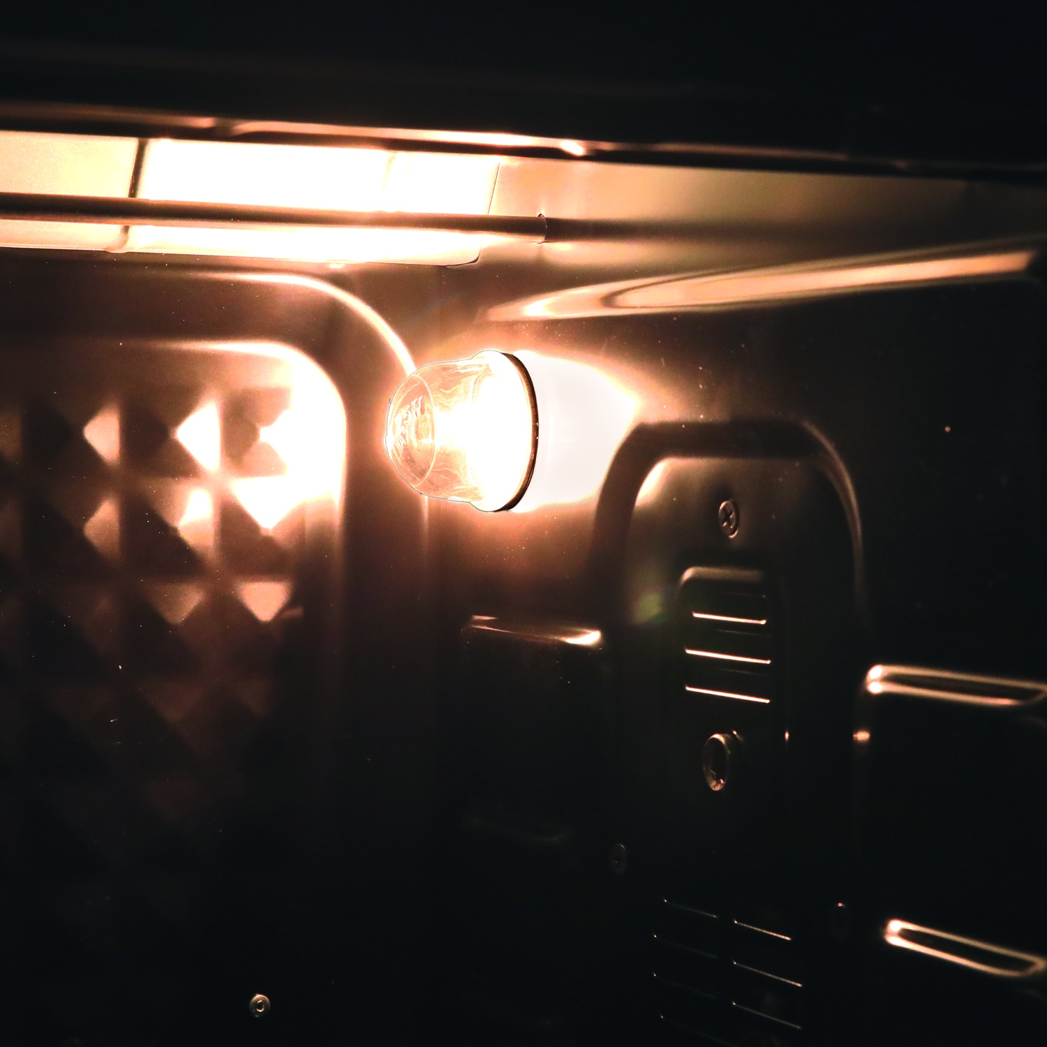 Una lampadina illumina l'interno di un forno scuro. Si vedono pareti metalliche.