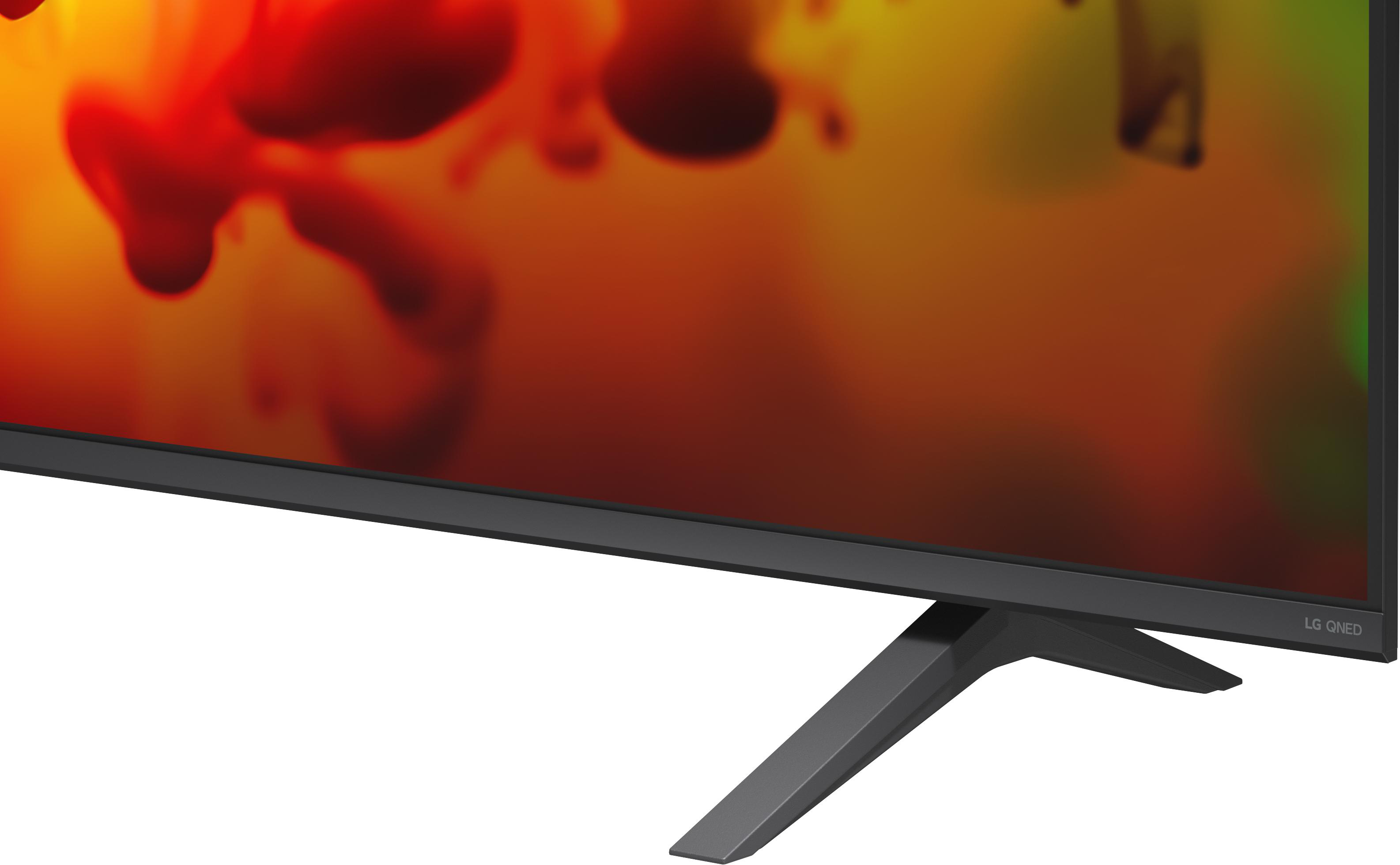 Ein schwarzer Fernseherfuß vor einem bunten Hintergrund mit roten und orangen Flecken.