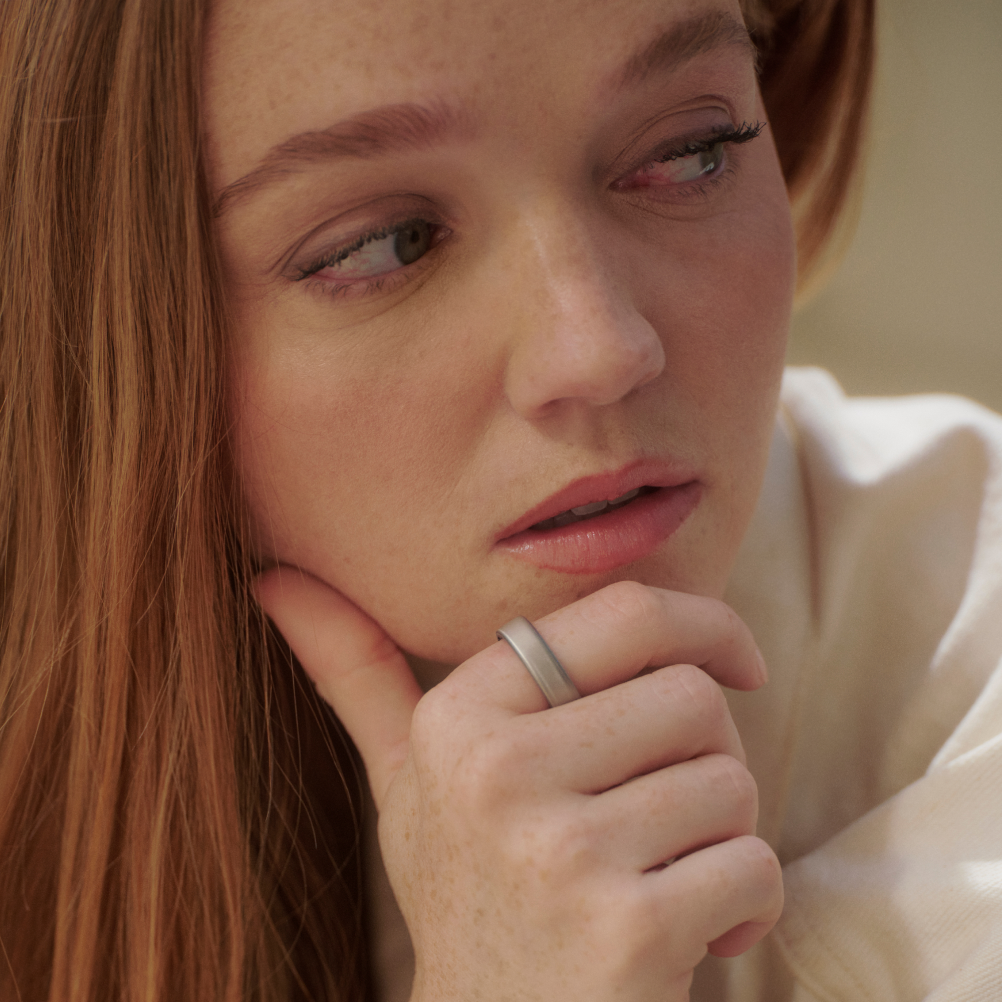 Gros plan d'une femme rousse regardant pensivement sur le côté.