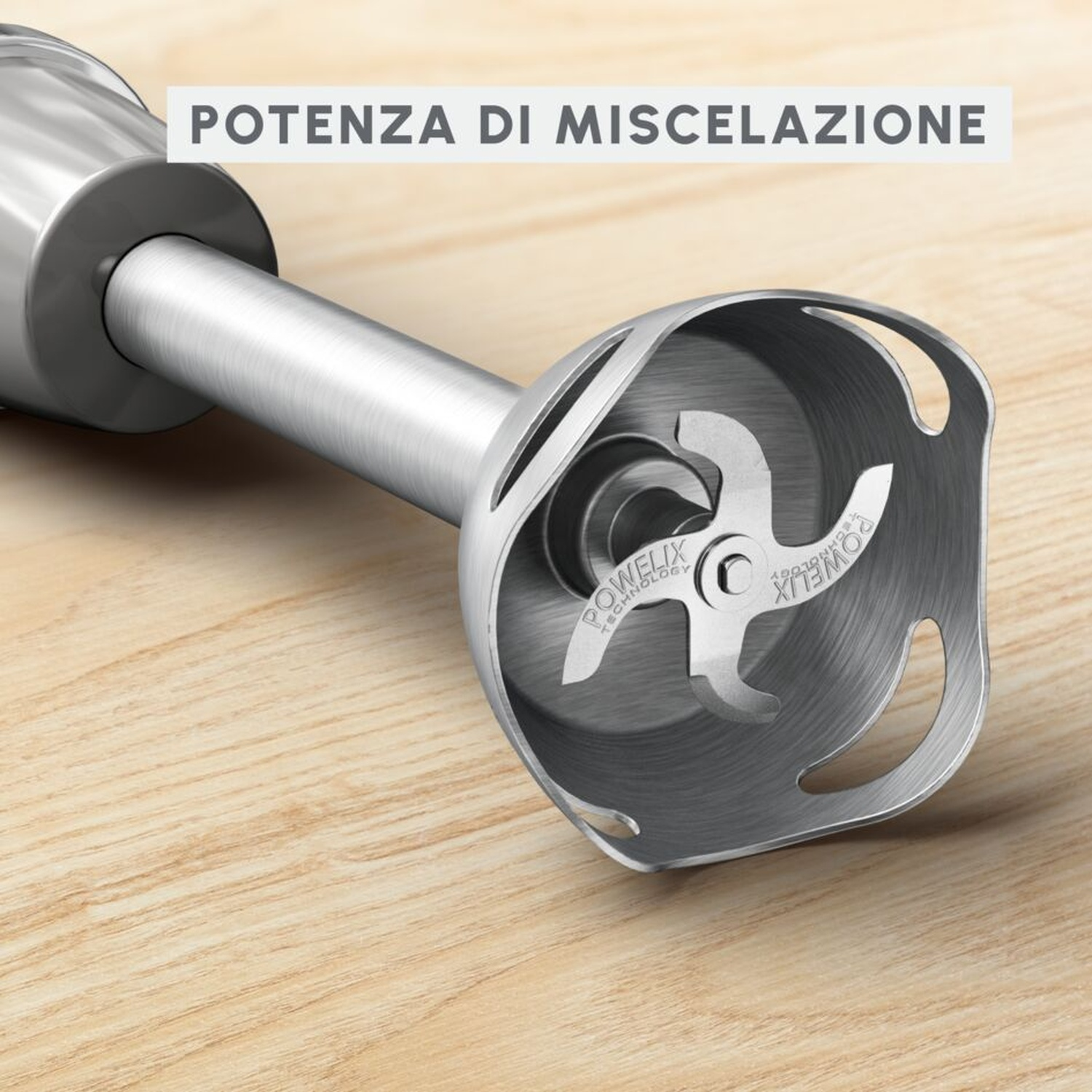 Primo piano di un frullatore a immersione argento con lame su tavolo in legno.