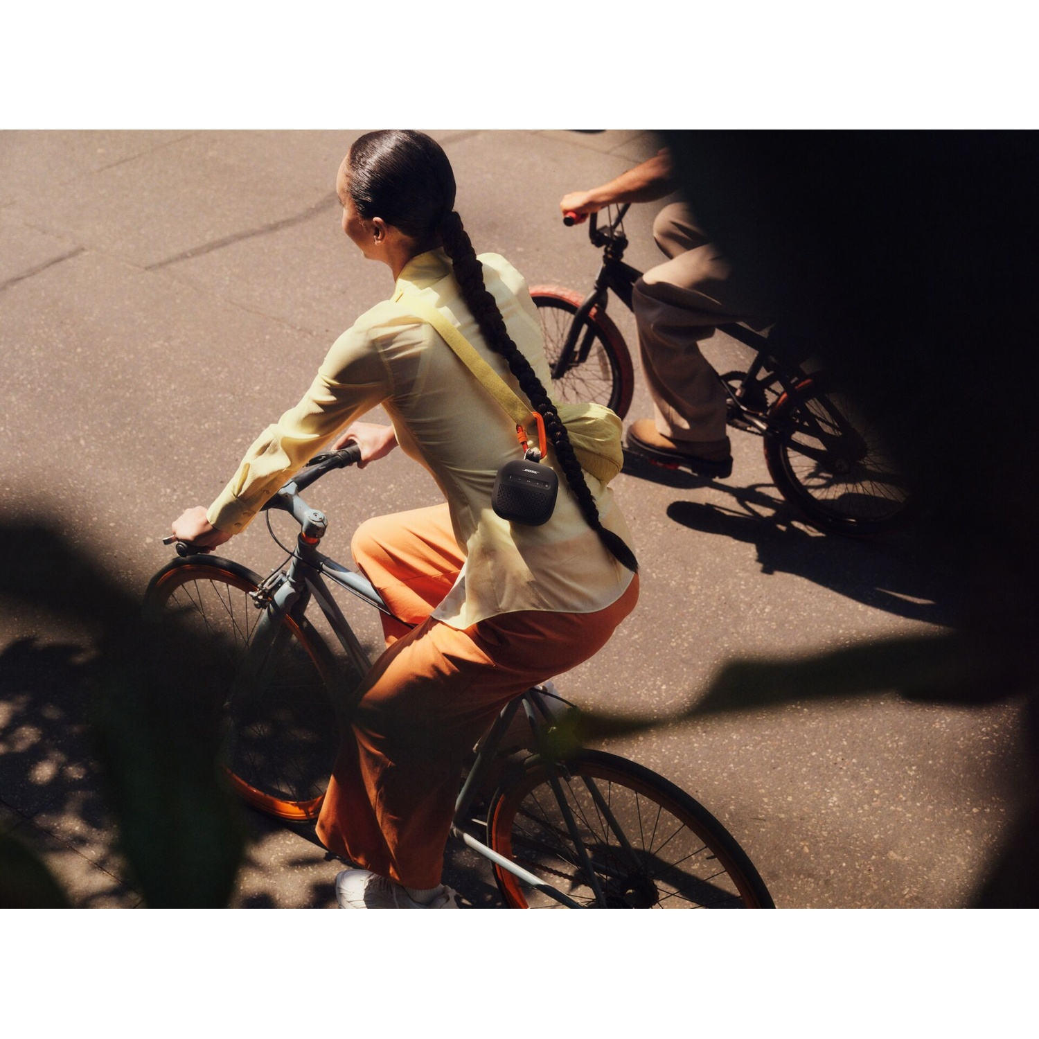 Twee mensen fietsen op straat, één in een geel shirt en oranje broek.