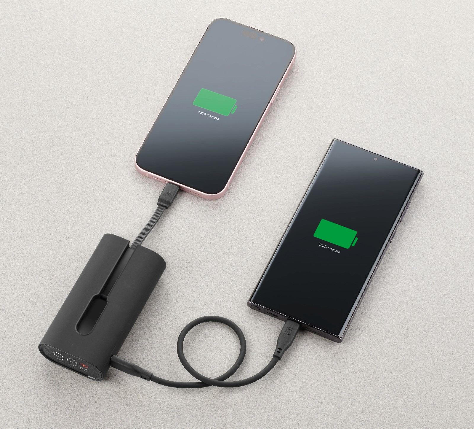 Dos smartphones se cargan con un cargador portátil negro. Ambos muestran 100% cargados.
