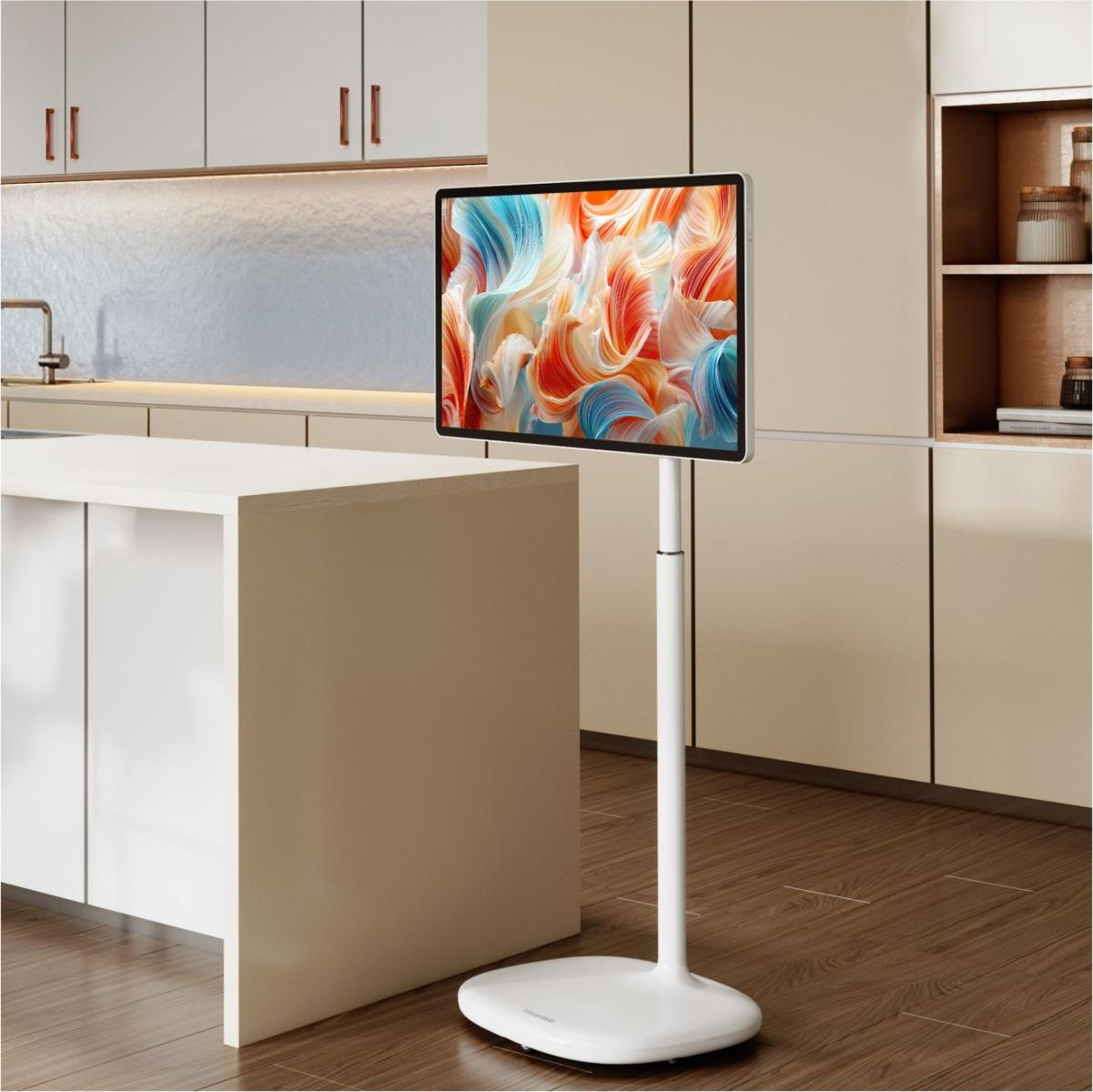 Ein moderner weißer Fernseher auf einem Standfuß steht in einer hellen Küche neben einer Insel.