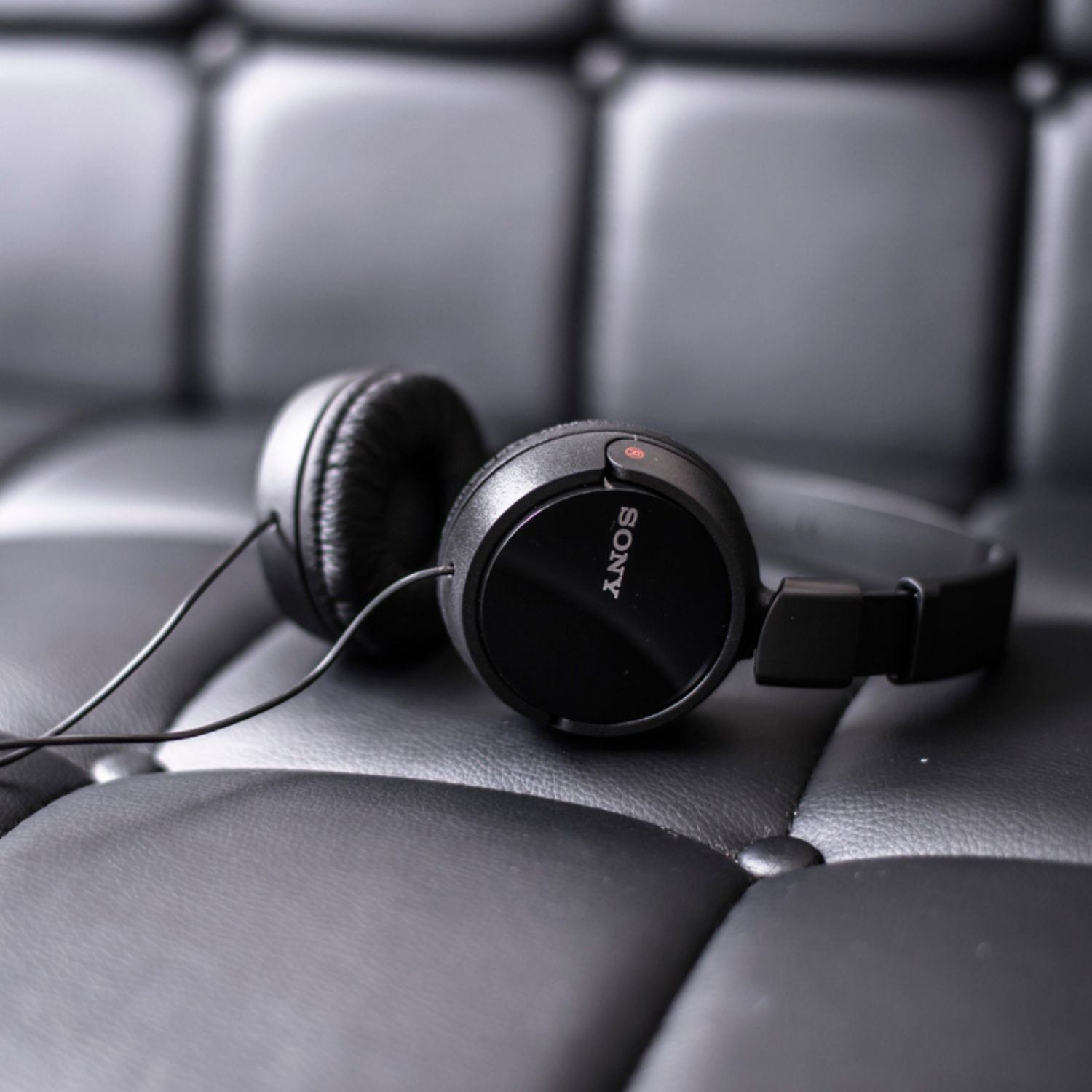 Auriculares Sony negros sobre una superficie de cuero negro capitoné. Vista cercana.