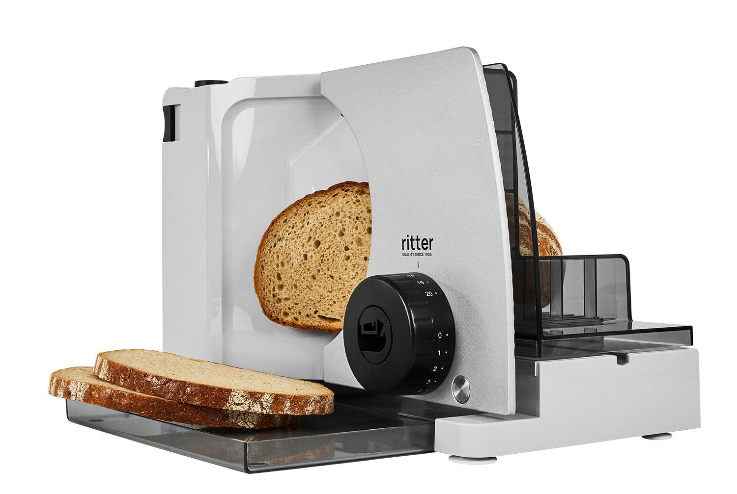 Ein weißer Brotschneider mit einem Brotlaib und zwei Scheiben daneben.