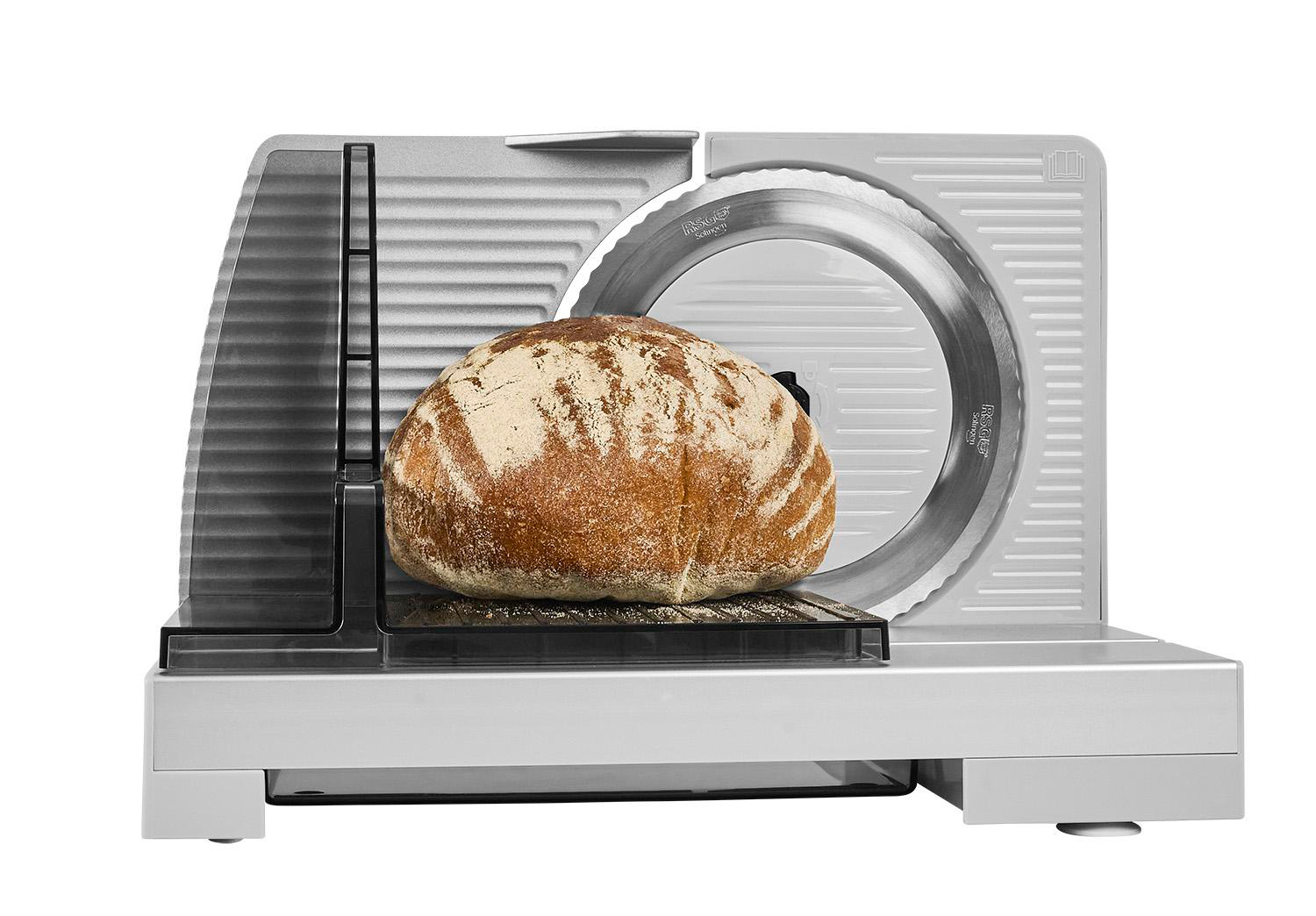 Ein Brot liegt auf einem Brotschneidegerät mit einem silbernen Messer.