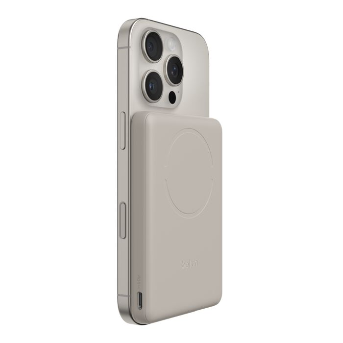 Un iPhone plateado con una batería MagSafe beige acoplada en la parte trasera.