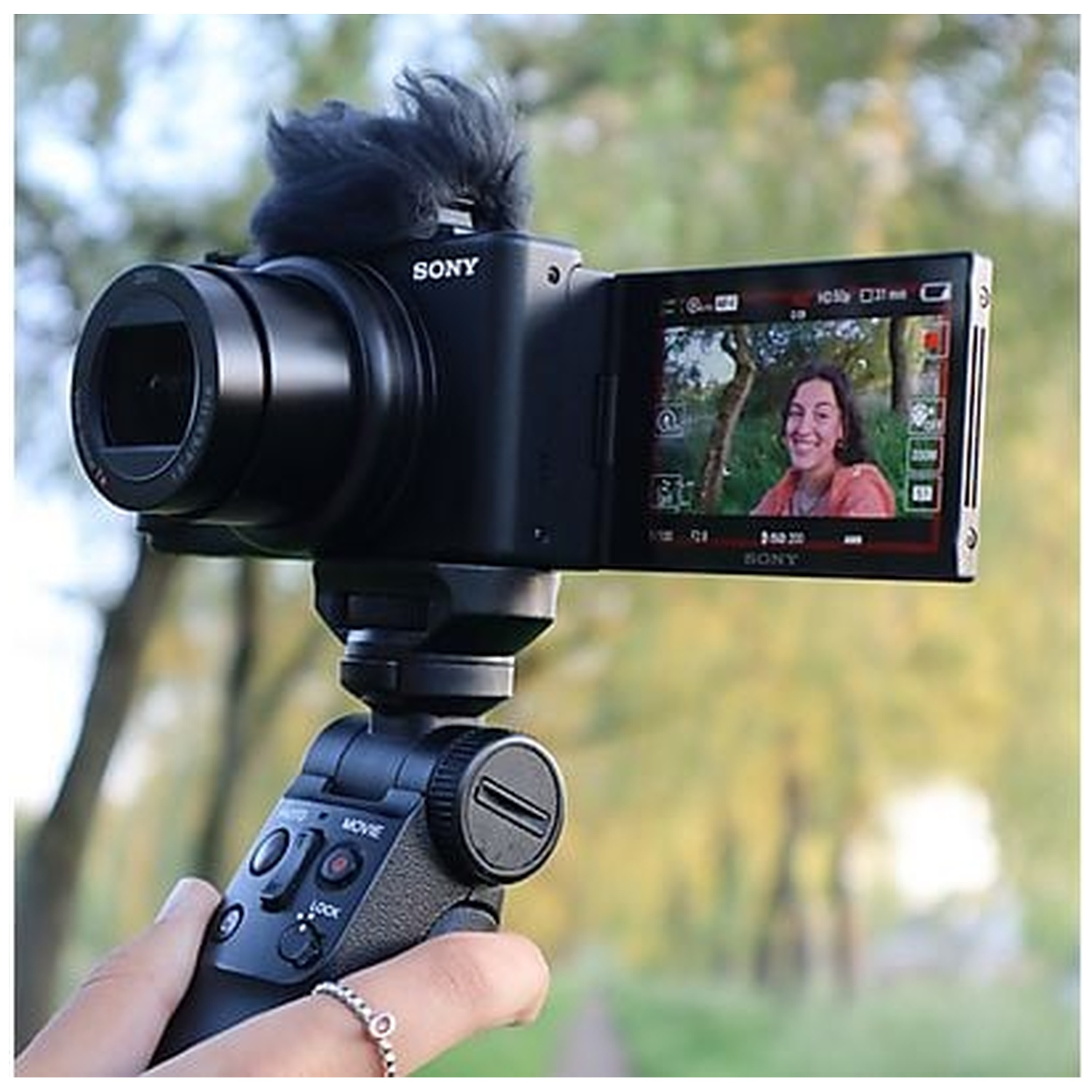 Une caméra Sony avec microphone et écran rabattable, montrant une femme souriante.