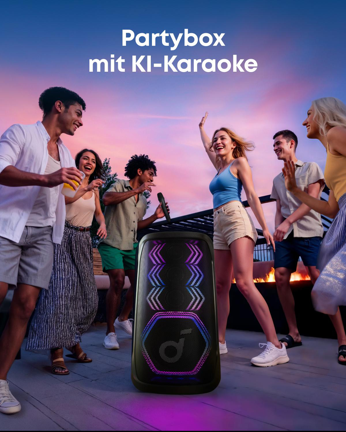 Gruppe feiert bei Sonnenuntergang mit Partybox und Mikrofon.