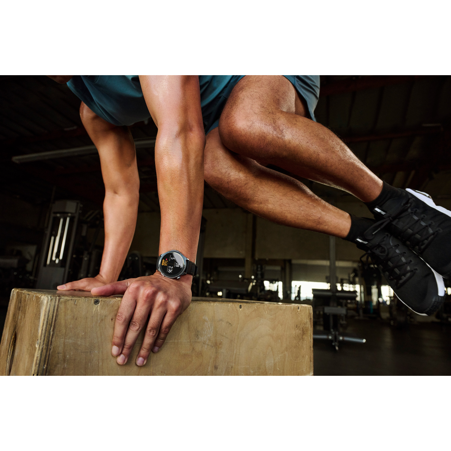Uomo fa un box jump in palestra. Indossa un orologio.