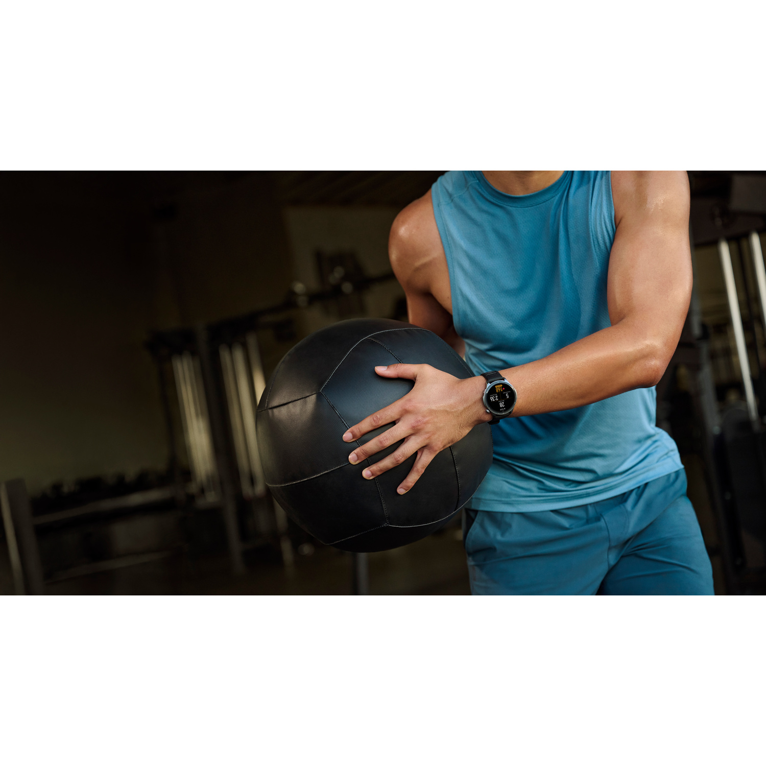 Un uomo in palestra tiene una grande palla medica nera.