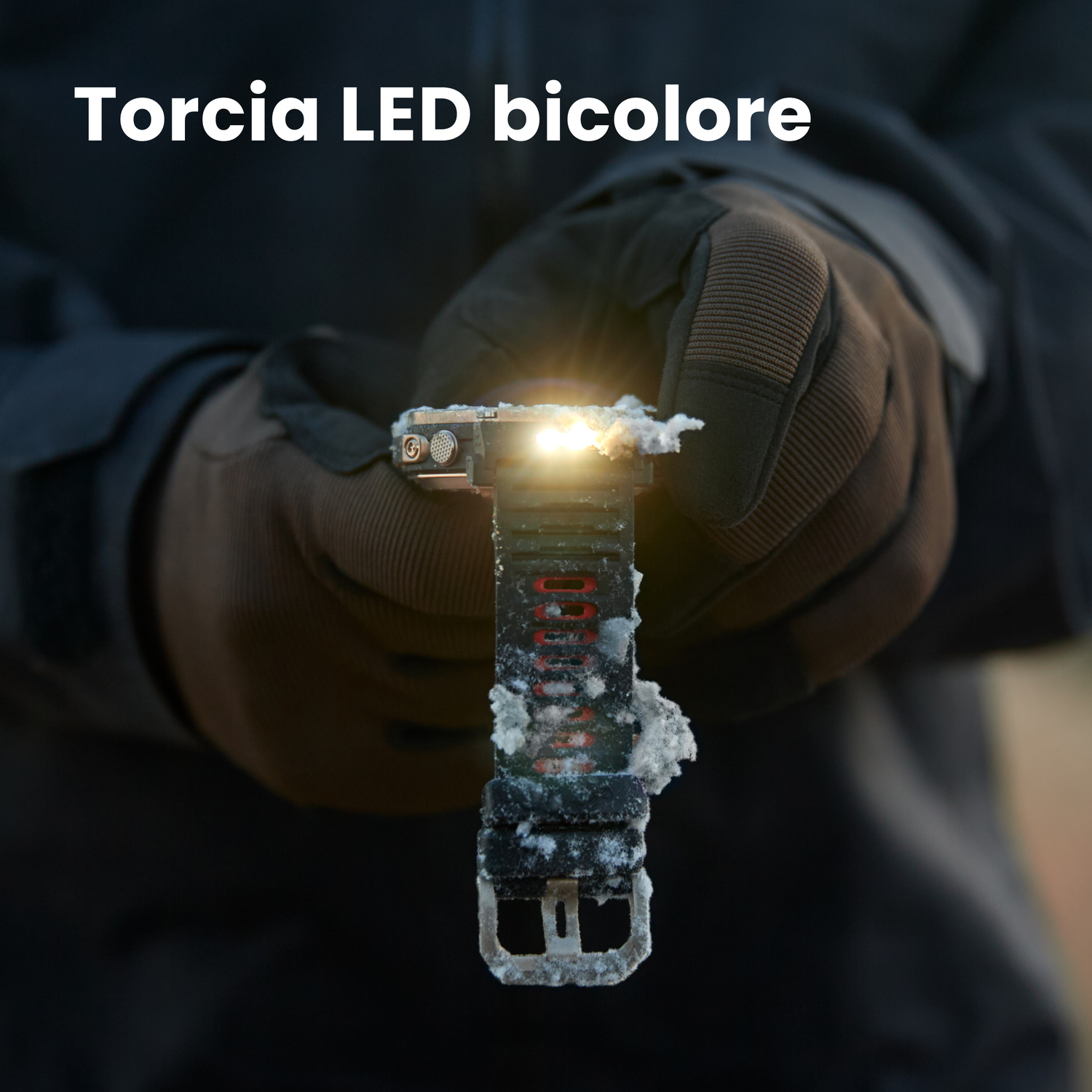 Una mano con guanto marrone tiene una torcia LED bicolore coperta di neve.