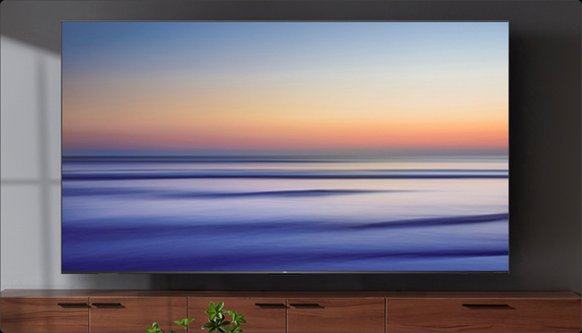 Un televisor moderno muestra una imagen abstracta de un atardecer sobre el mar.