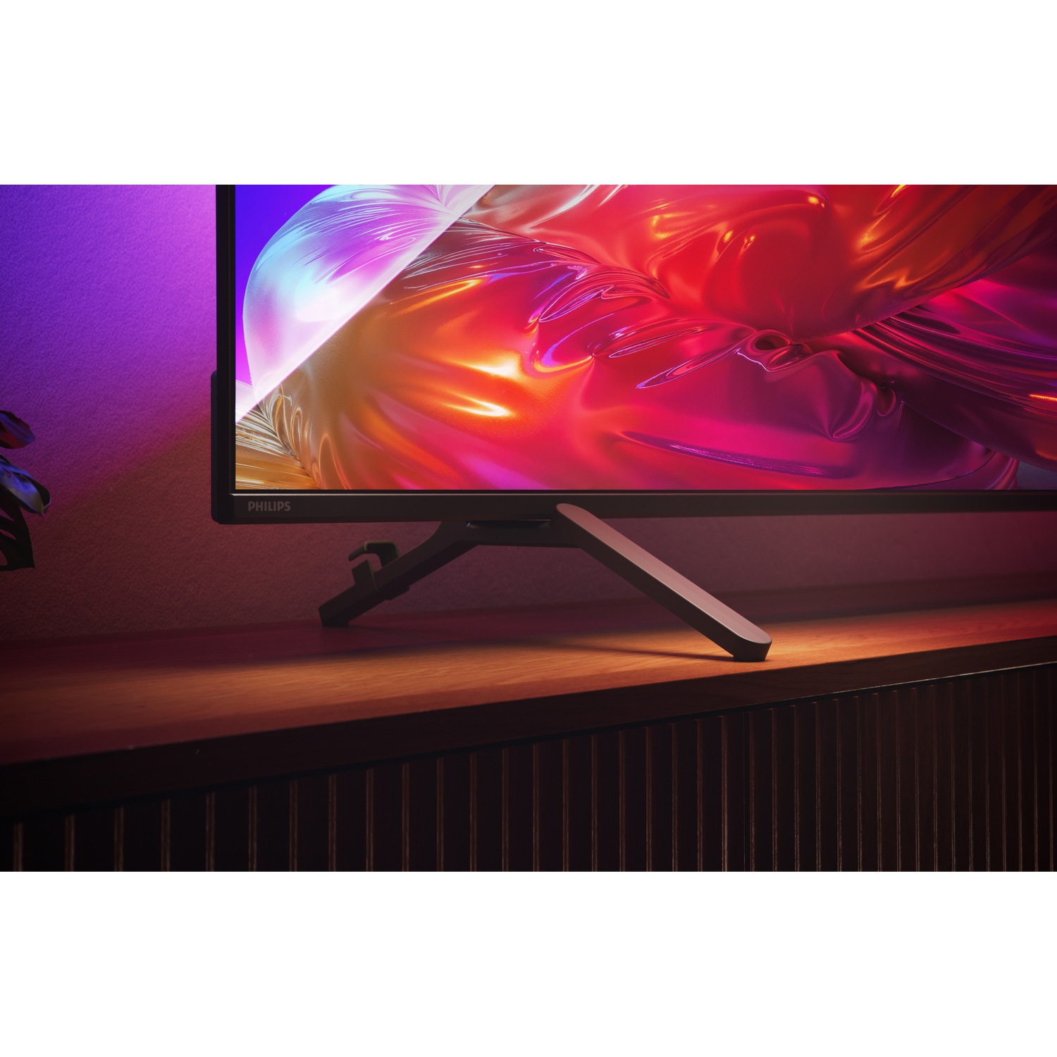 A Philips monitor displays vibrant red and purple abstract art, with ambient purple light on the left.