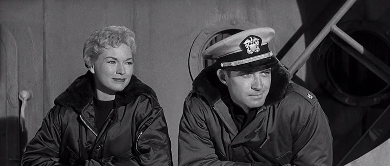 Ein Mann in Uniform und eine Frau sitzen nebeneinander und blicken nach rechts.