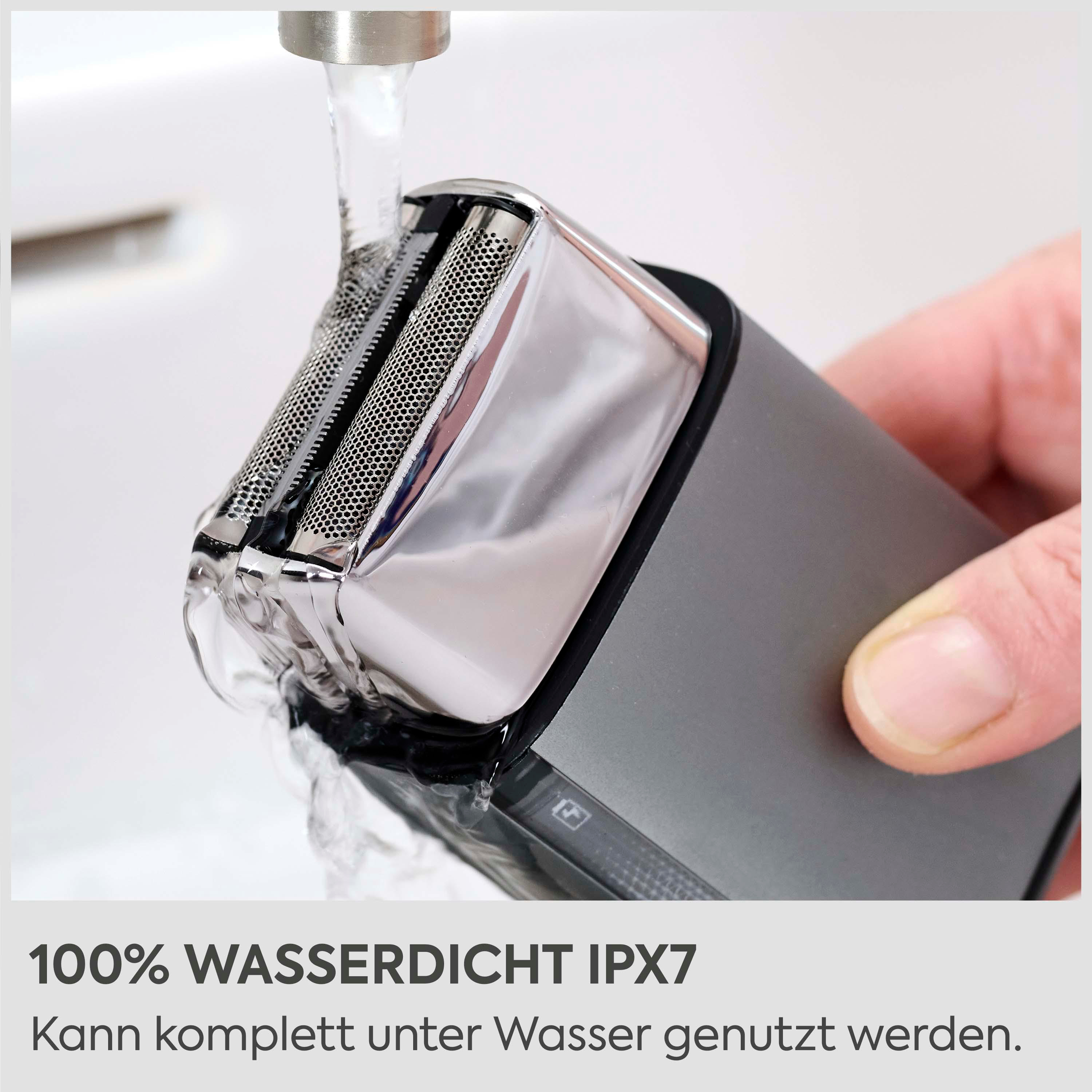 Ein Elektrorasierer wird unter fließendem Wasser gehalten. Nahe Aufnahme.