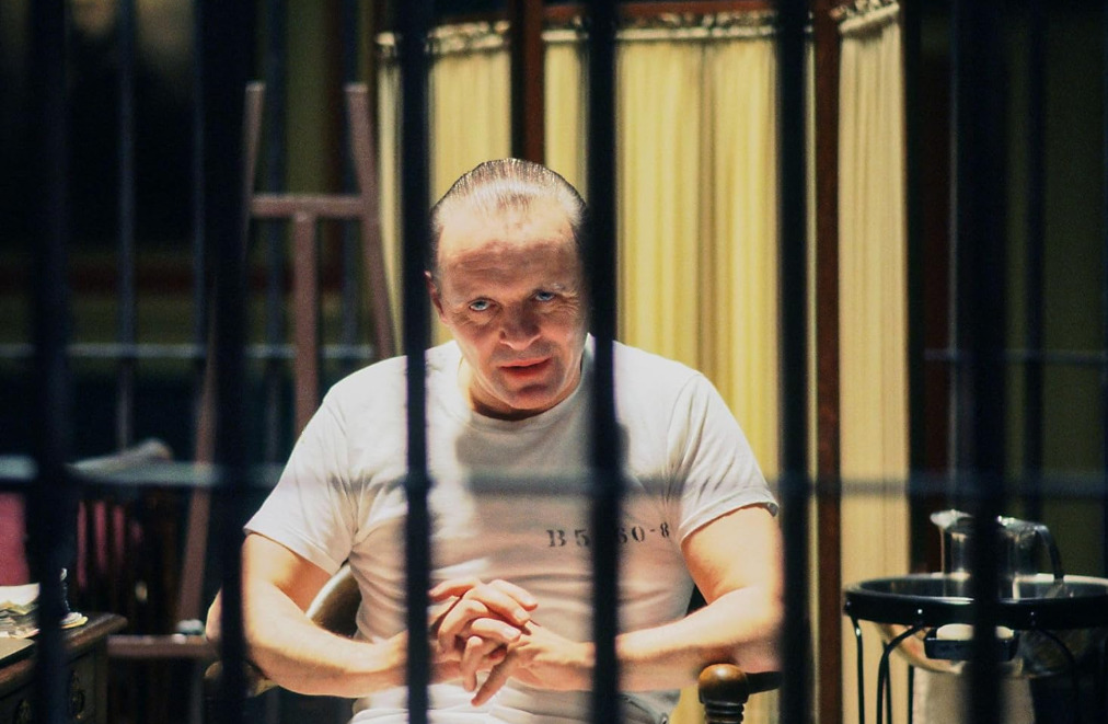 Ein Mann in einem weißen T-Shirt sitzt hinter Gittern in einem Gefängnis.