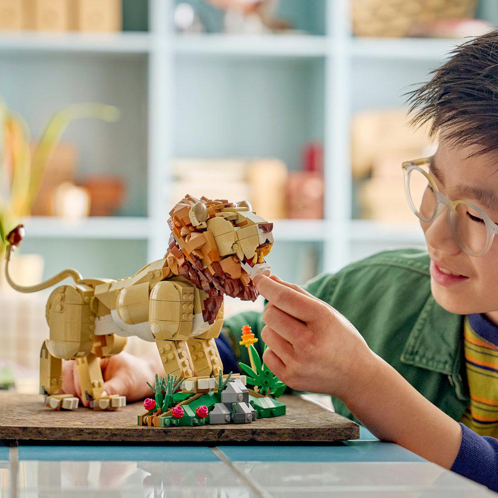 Ein Junge baut einen Lego-Löwen mit einem kleinen grünen Beet und Blumen.